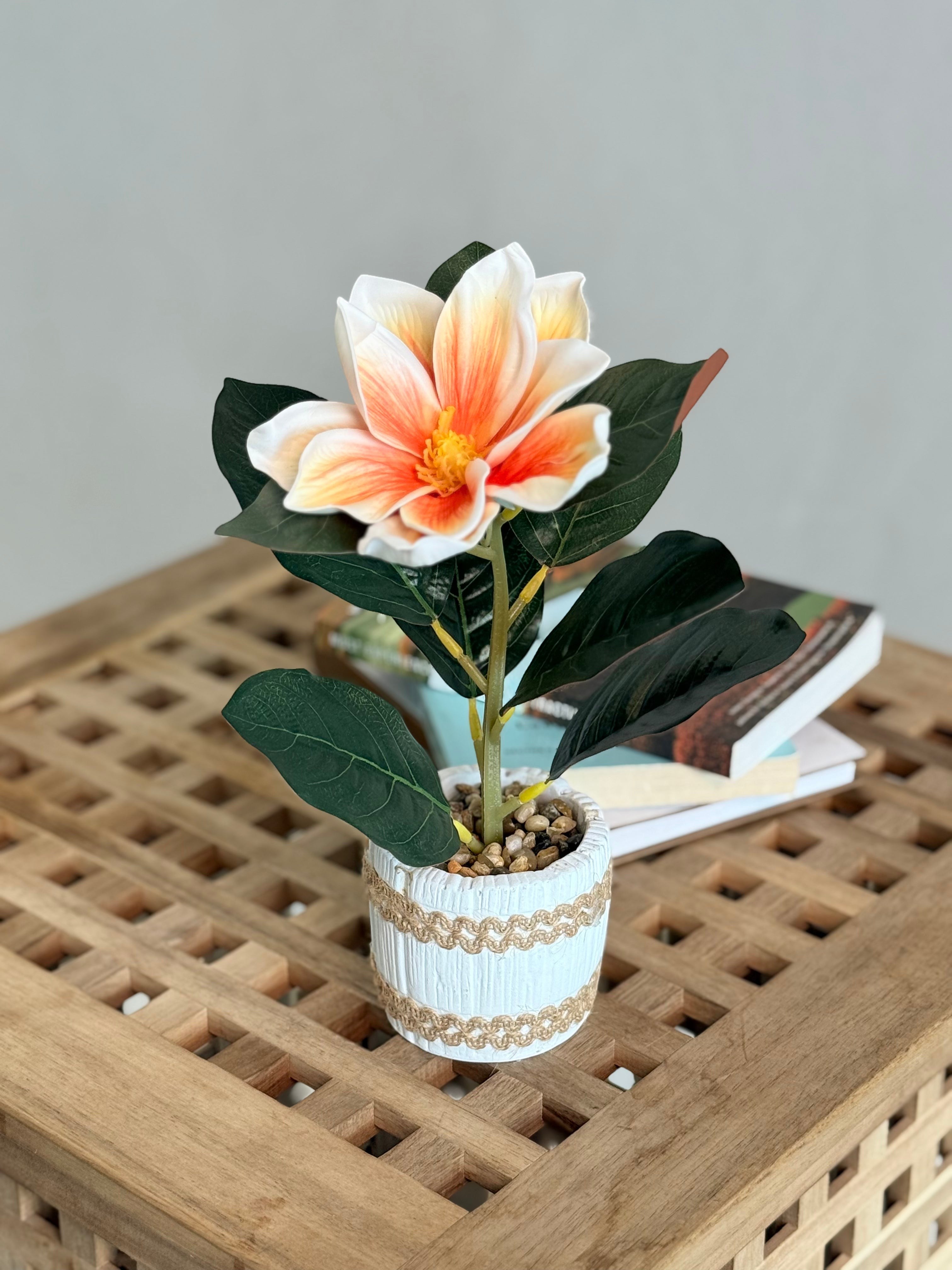 High Objects artificial lily plant with orange and white petals in a white ceramic pot with pebbles and jute trim.