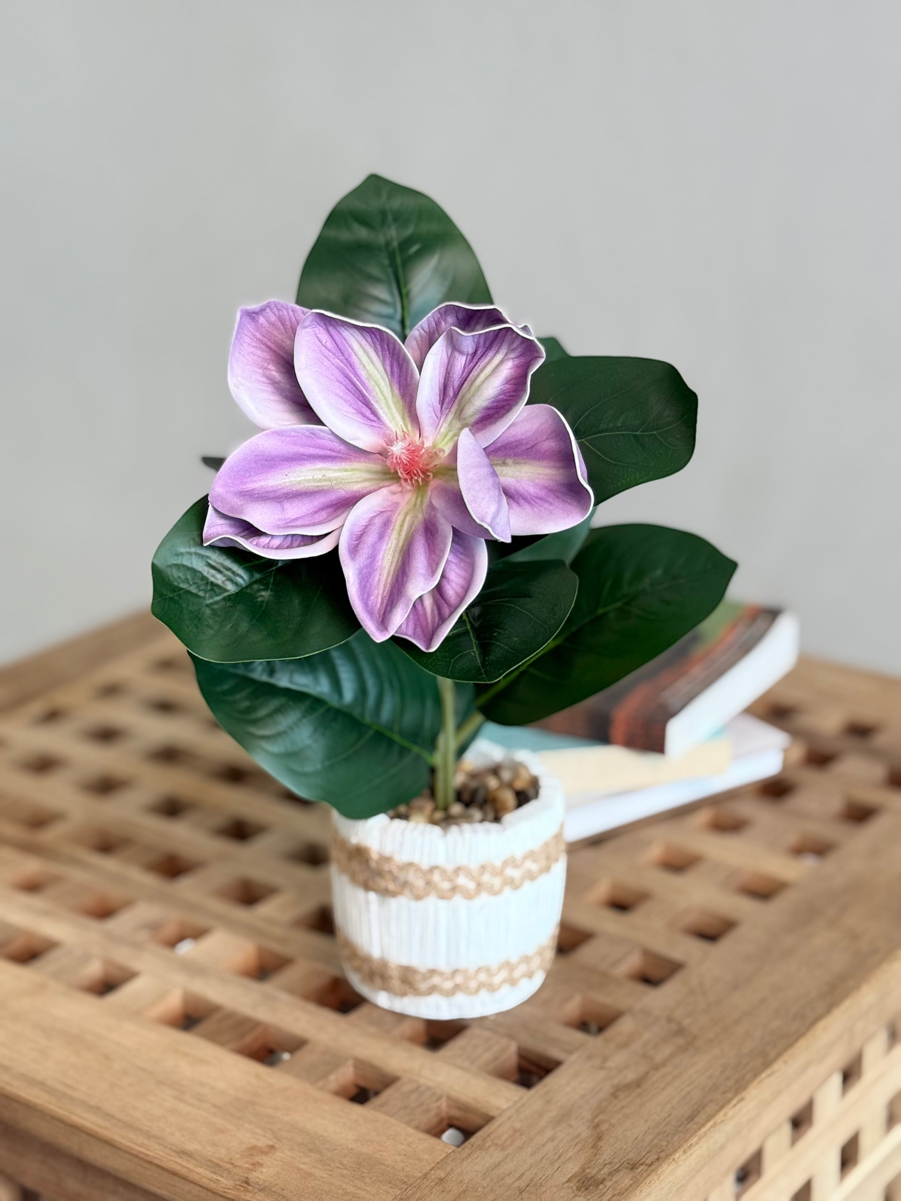 High Objects artificial lily plant with purple and white petals, green leaves, in a white striped ceramic pot with pebbles.