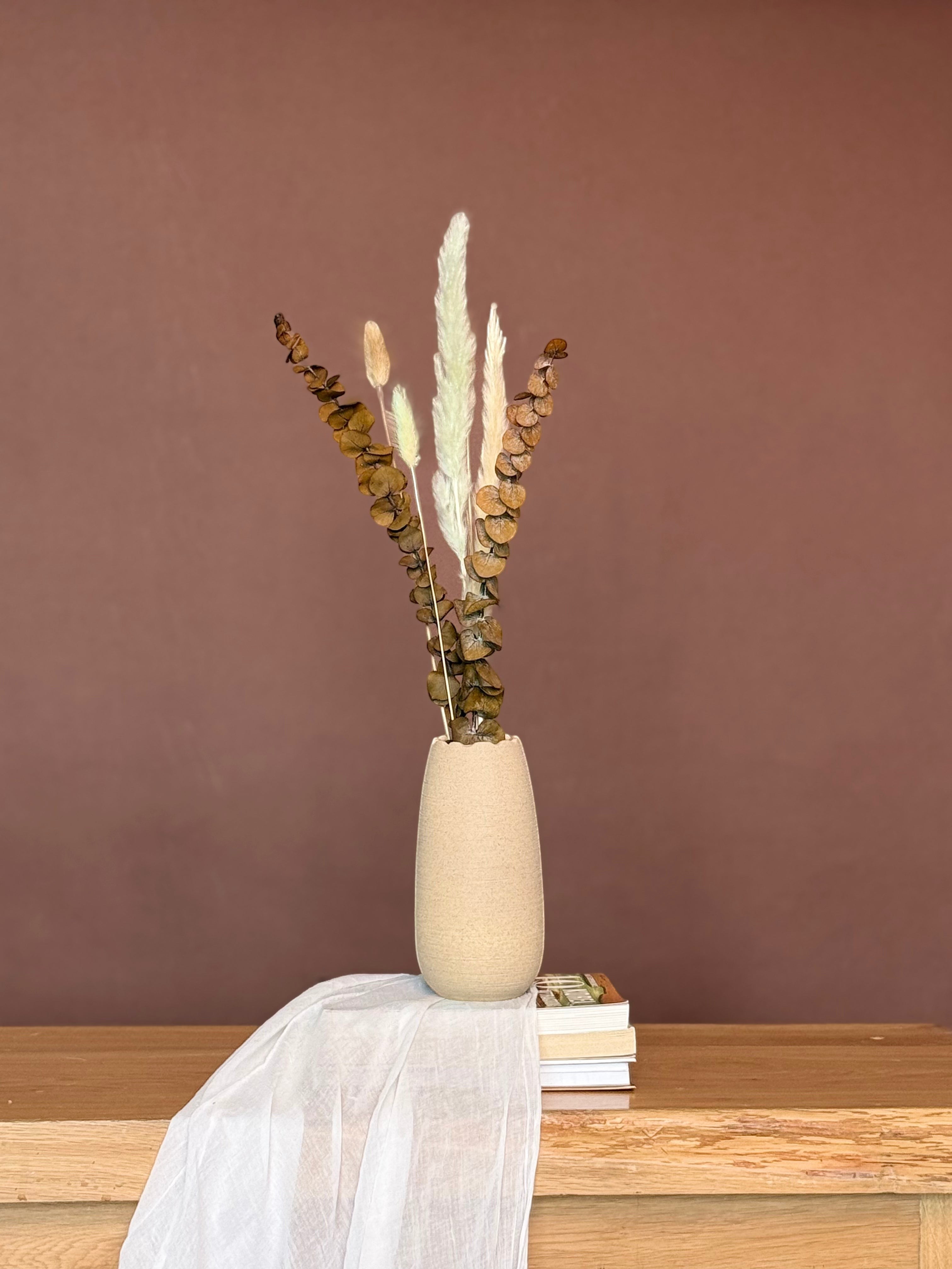 High Objects beige textured ceramic vase with dried eucalyptus and pampas grass arrangement on a wooden table.