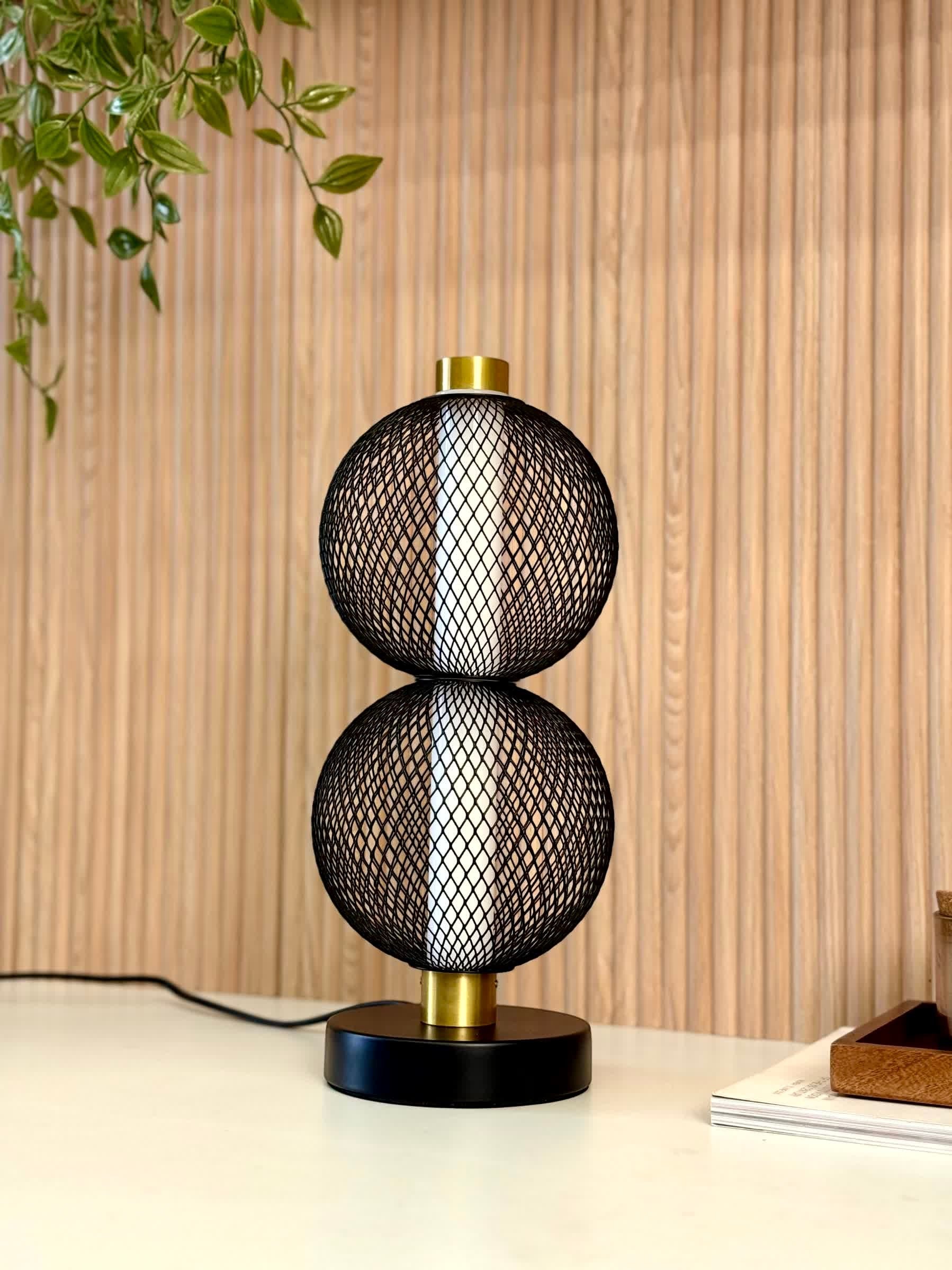 High Objects Celeste Duo Mesh Table Lamp with stacked black mesh spheres and brushed gold accents on a black base.