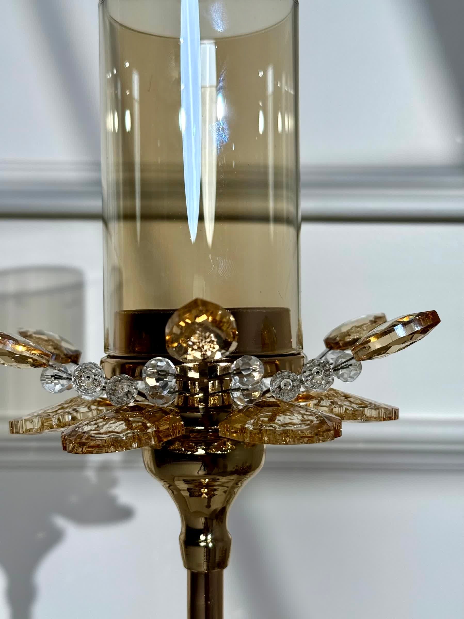 High Objects Crystal Bloom candle stand with amber glass hurricane and crystal petal accents. Elegant gold finish.