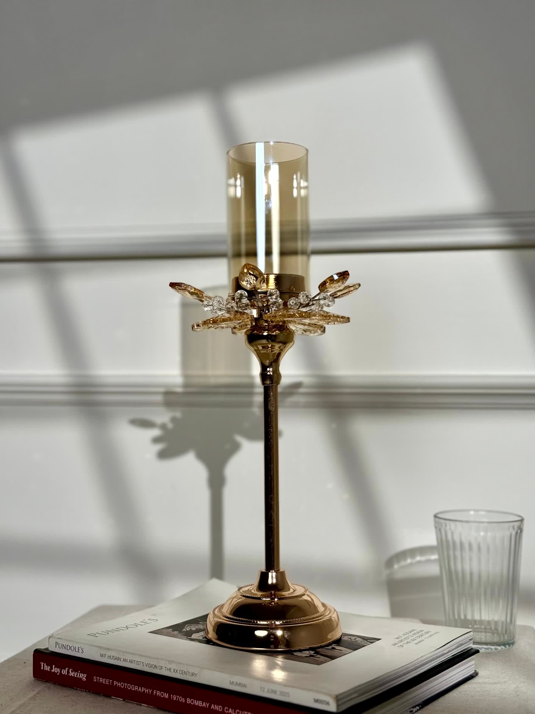 High Objects Crystal Bloom candle stand with amber glass hurricane and crystal petal accents on a rose gold base.