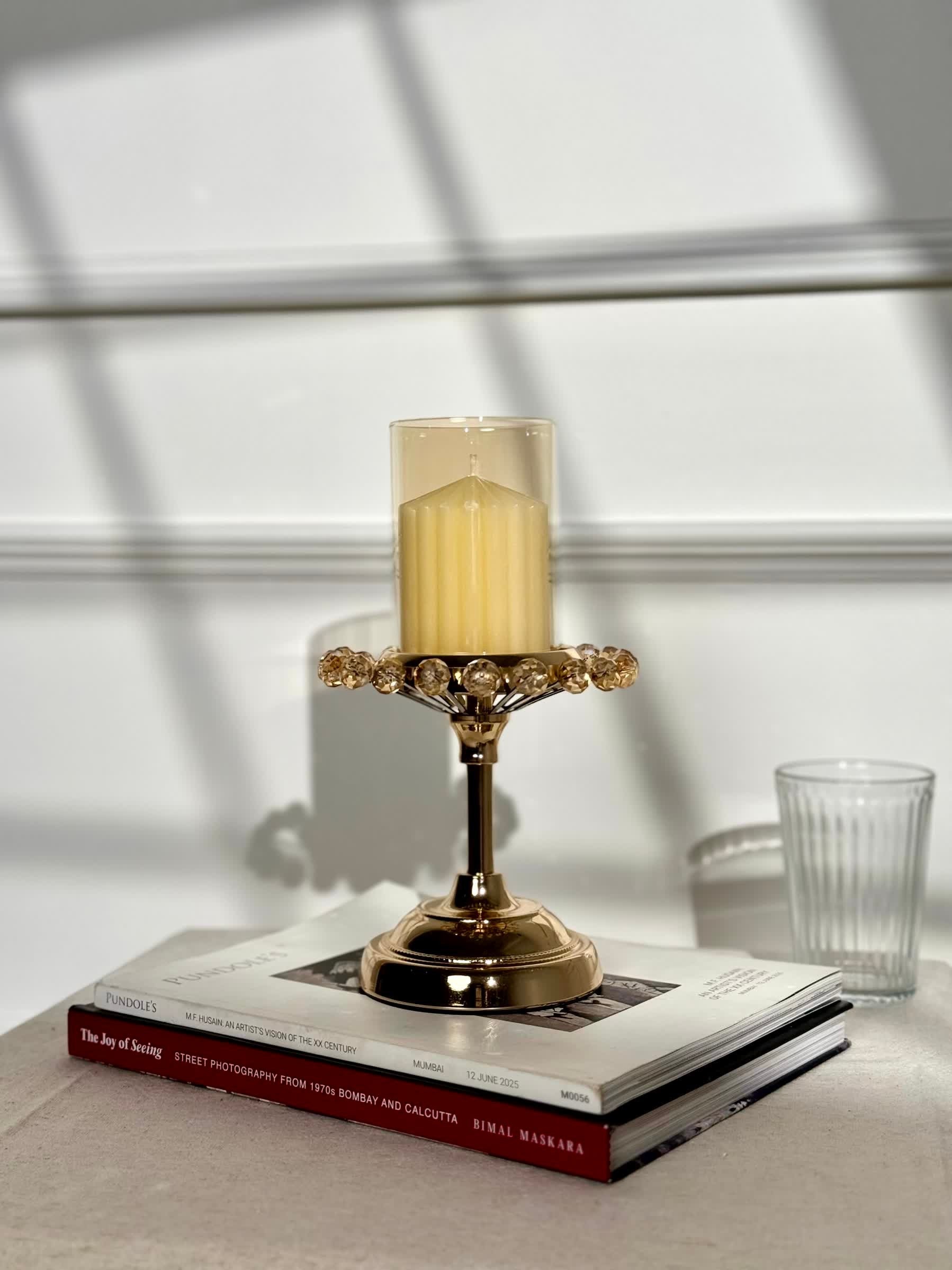 High Objects gold candle stand with crystal halo and tinted glass holder, topped with a yellow pillar candle.
