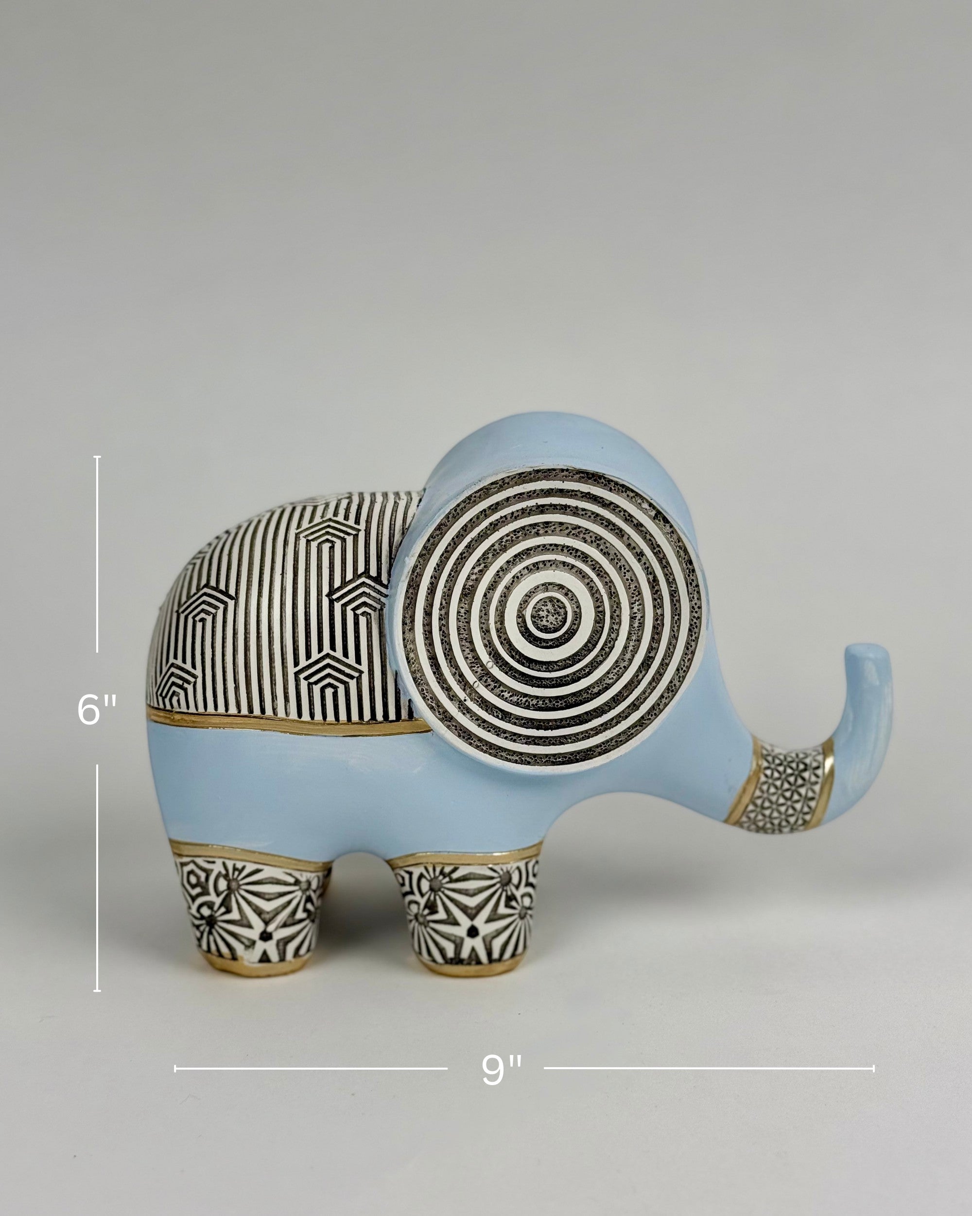 High Objects Elysian Trunk Figurine, a soft blue polyresin elephant with black and gold geometric patterns on its body and ears.