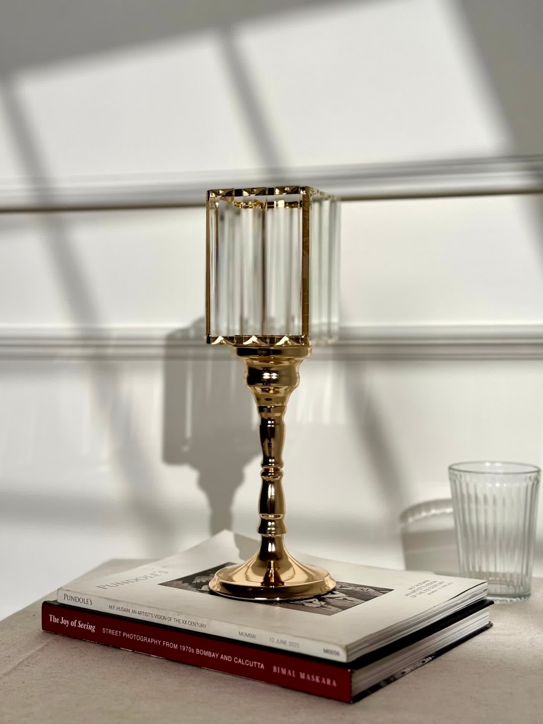 High Objects gold metal and clear glass candle stand with faceted hurricane top and pedestal base.