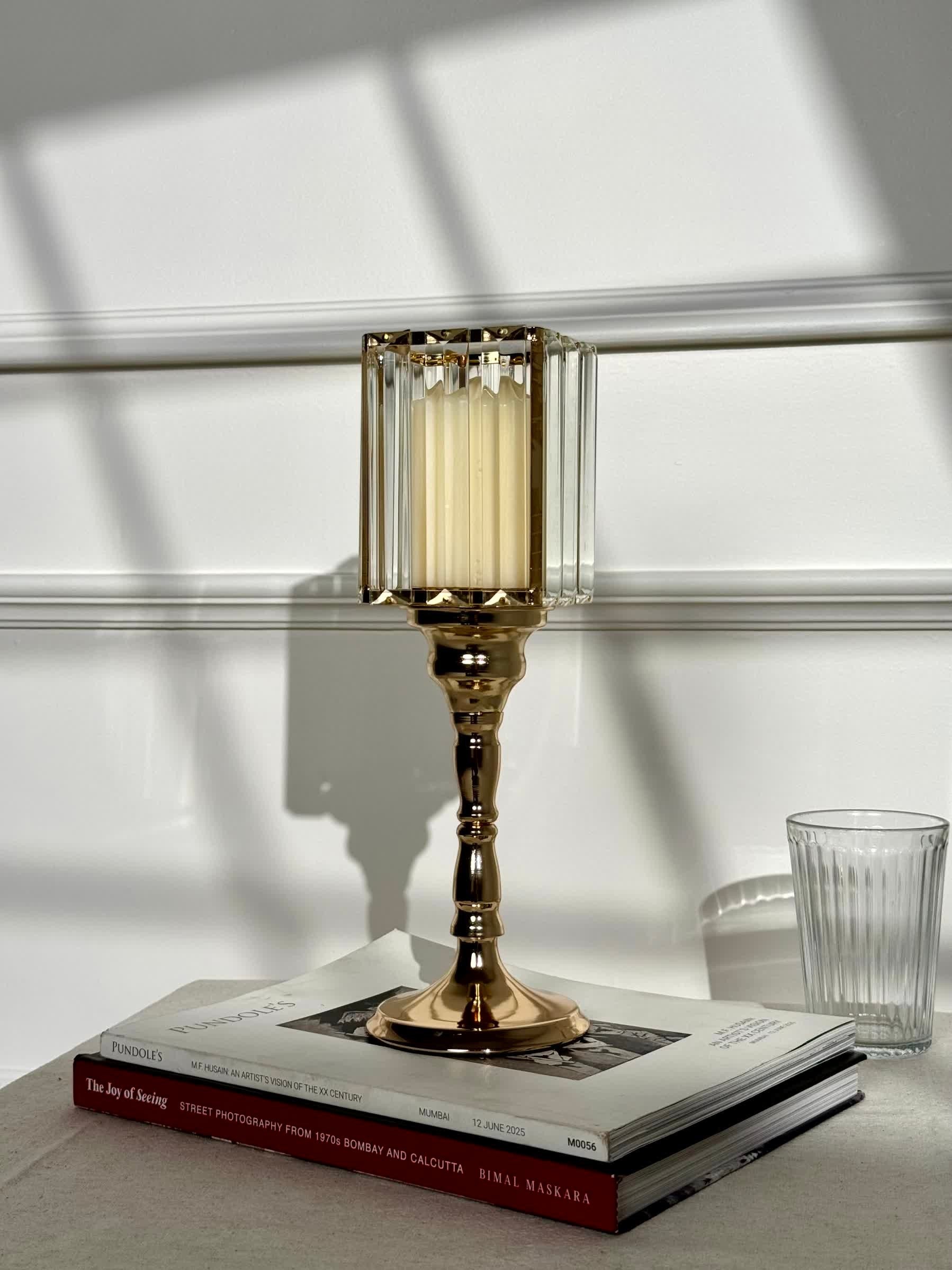 High Objects gold metal candle stand with faceted glass hurricane top and cream pillar candle.