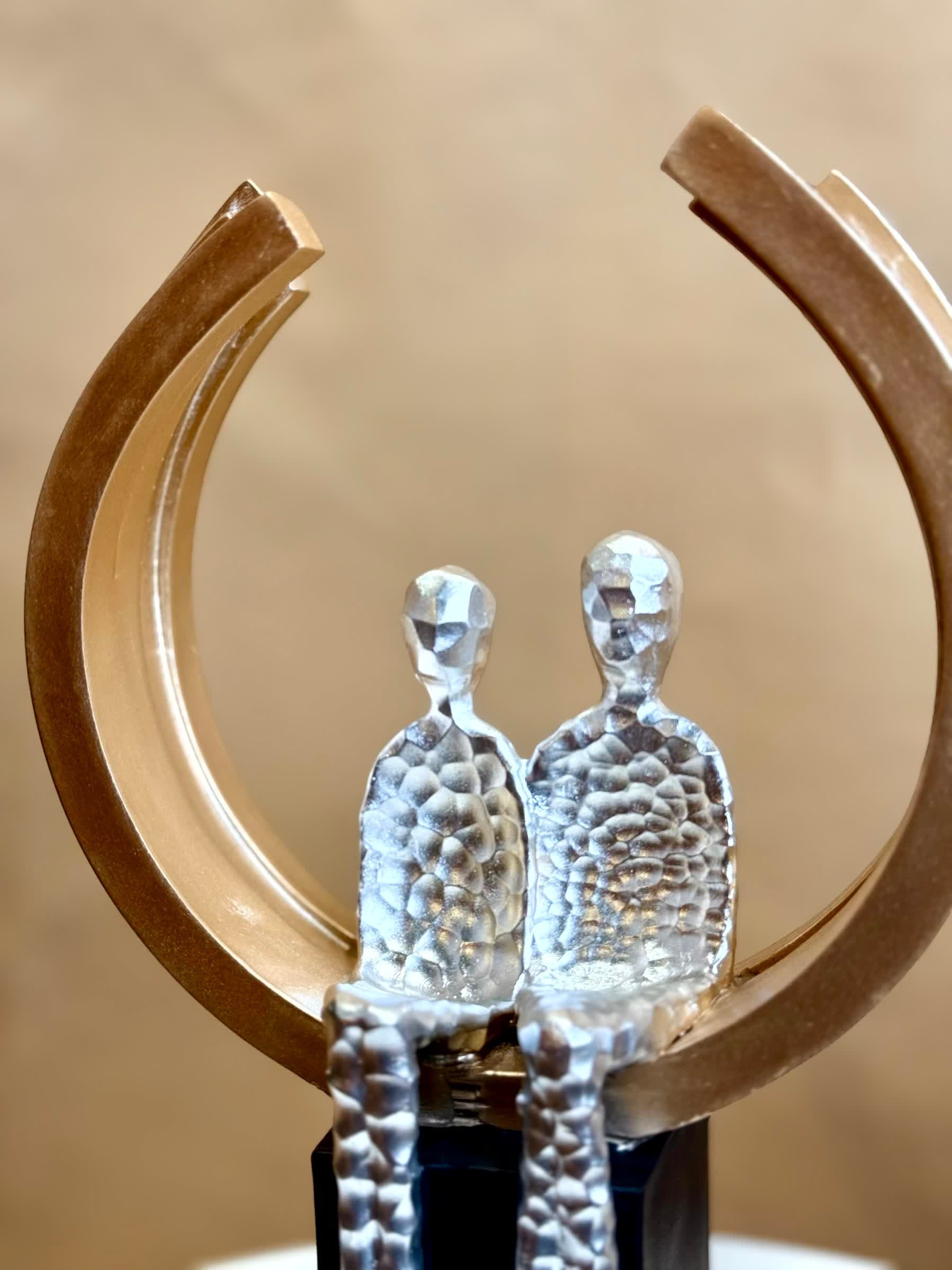 High Objects Golden Arc of Love showpiece with hammered silver finish couple in a gold ring on black base.