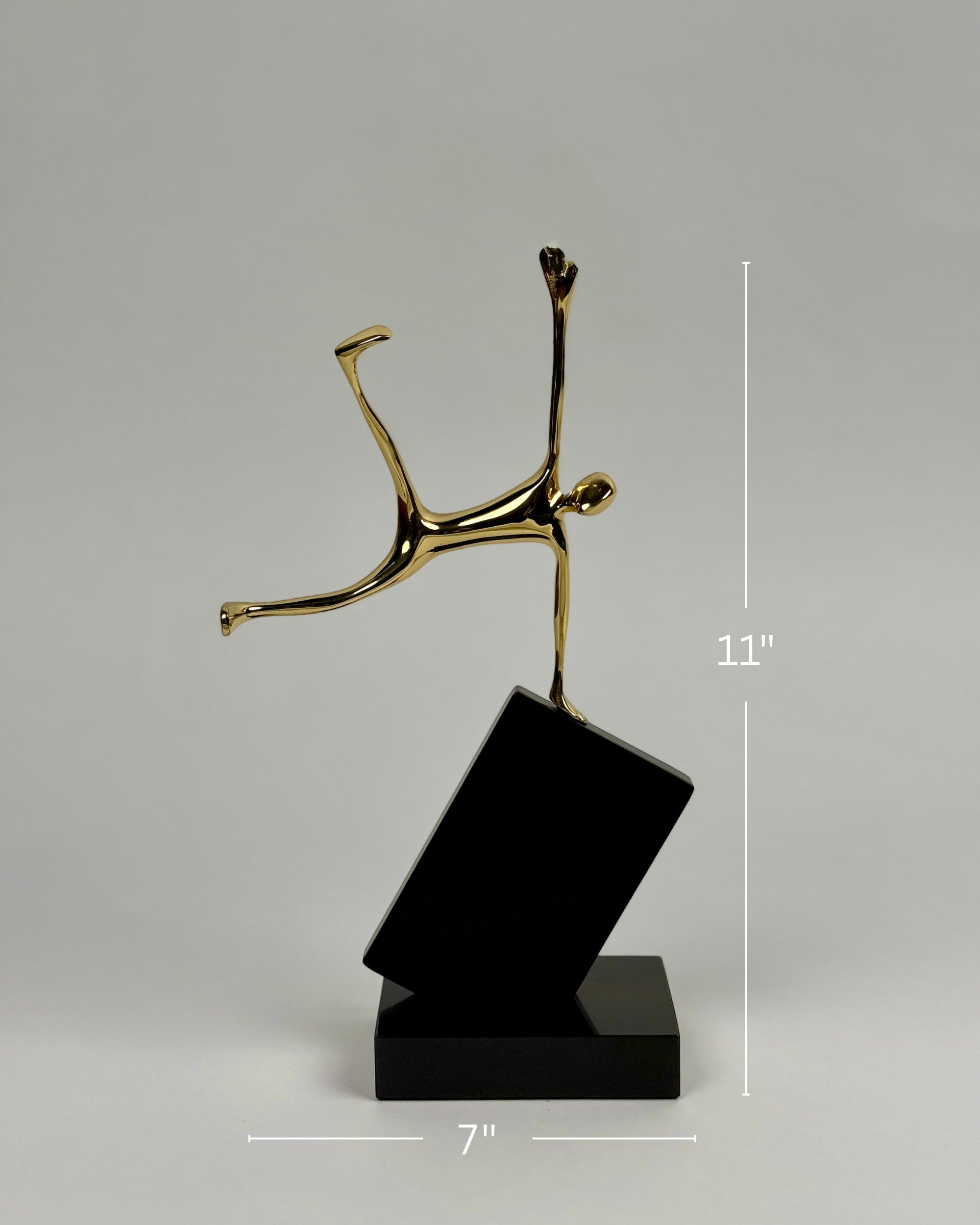 High Objects Golden Balance Artefact, abstract metal sculpture of a figure balancing on a tilted black block.