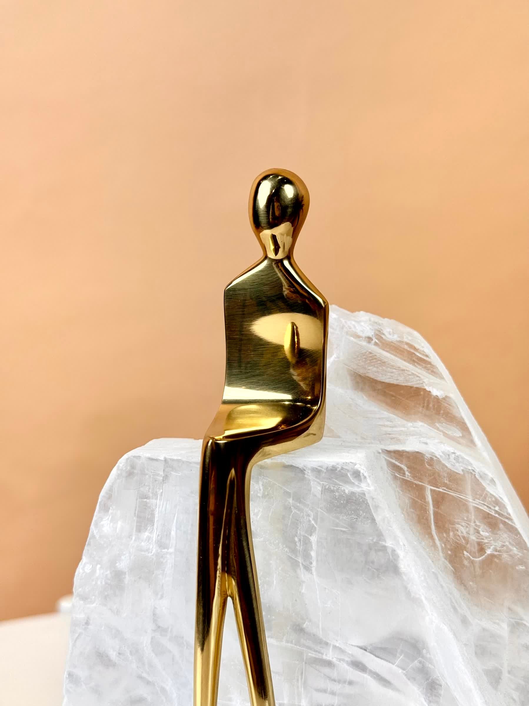 High Objects Golden Poise abstract figure sculpture in polished gold-finished iron on a natural crystal base.