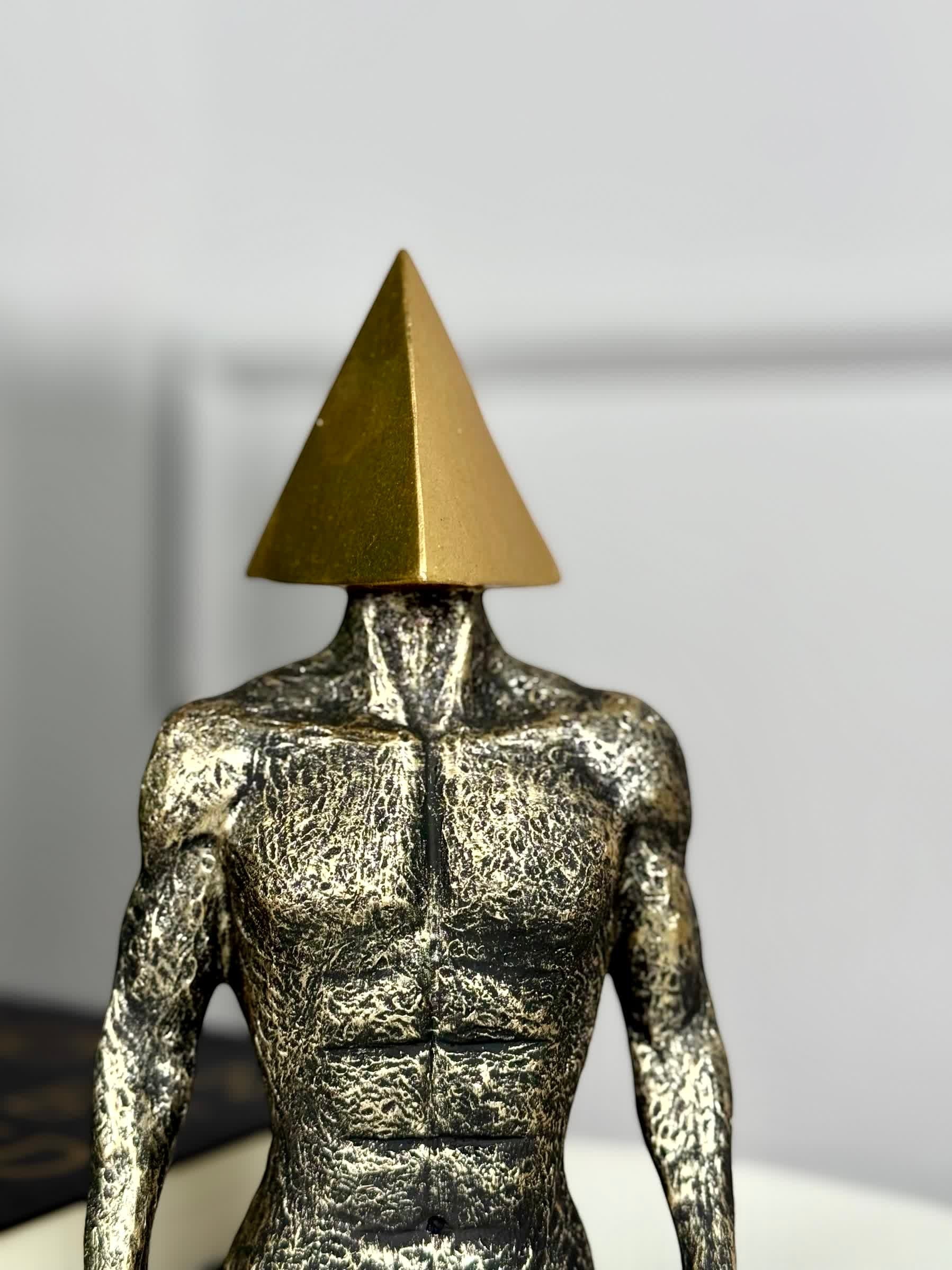 High Objects abstract sculpture of a muscular torso with a gold pyramid head, textured stone-like finish.