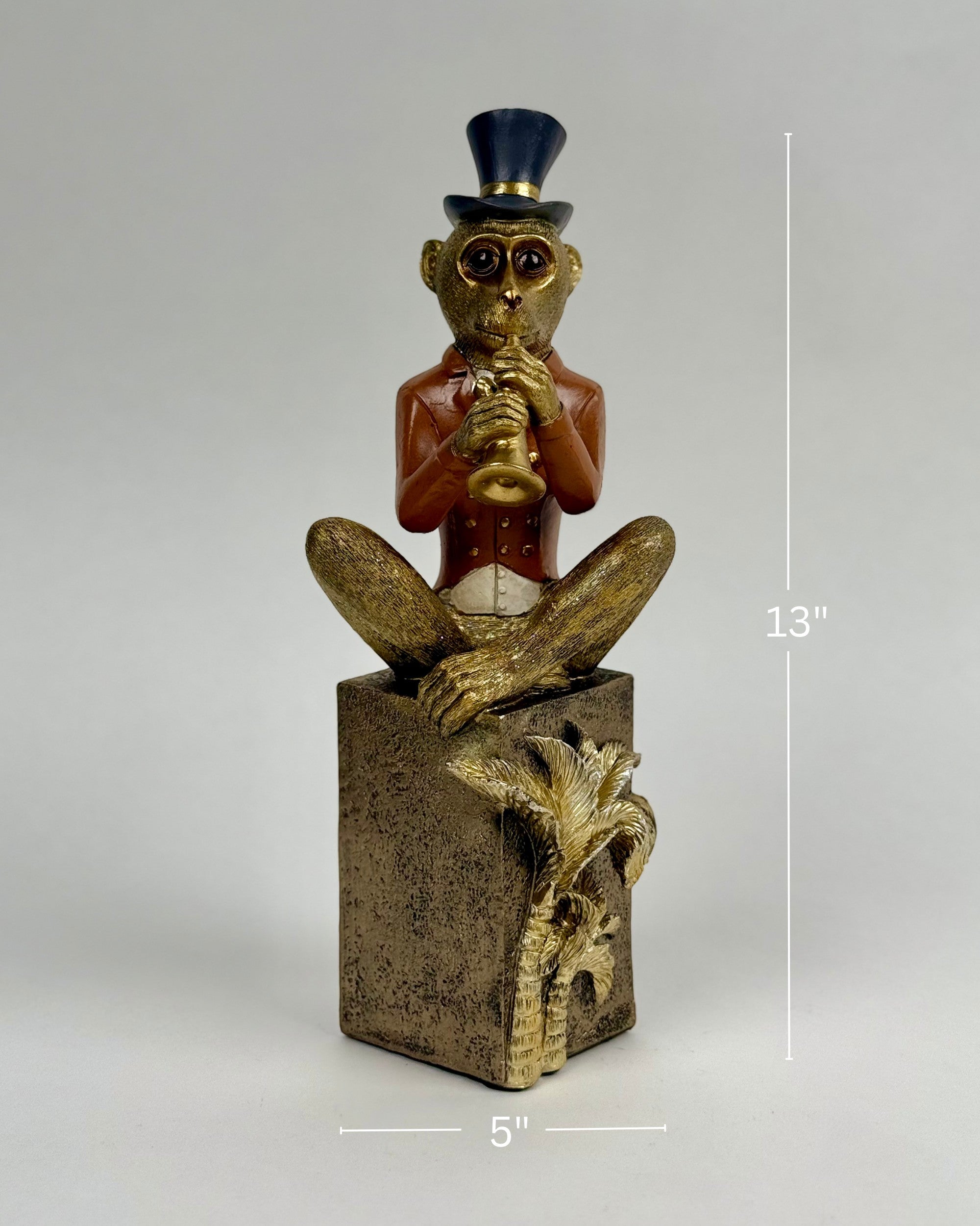 High Objects Golden Serenade Monkey showpiece in a red jacket and top hat playing a trumpet, seated on a textured pedestal.