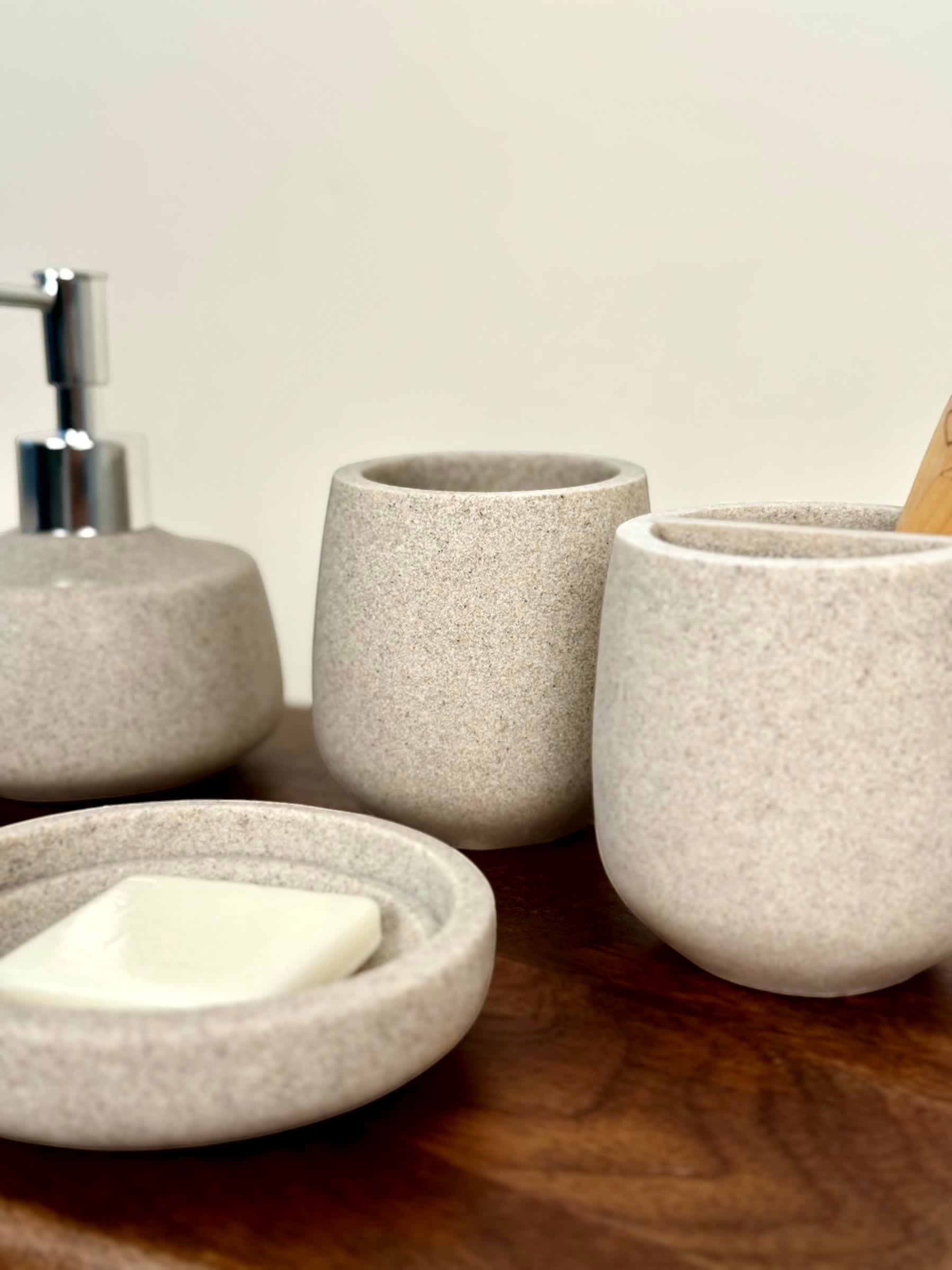 High Objects Pebbleease speckled stone bathroom accessory set with soap dish, soap dispenser, and toothbrush holder.