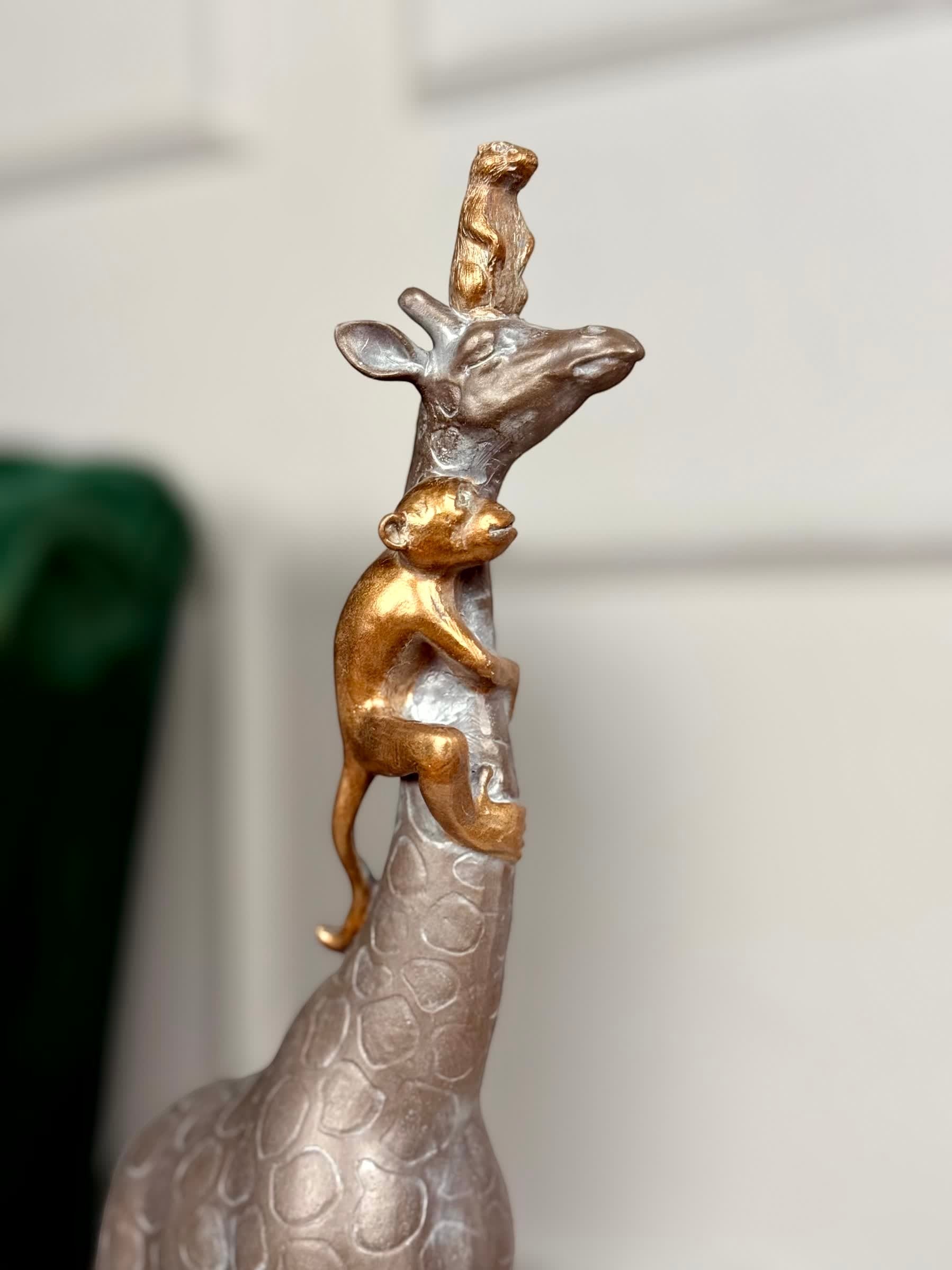 High Objects Savannah Majesty Showpiece sculpture of a giraffe with a monkey climbing its neck and a small animal on its head. Polyresin, dark finish.