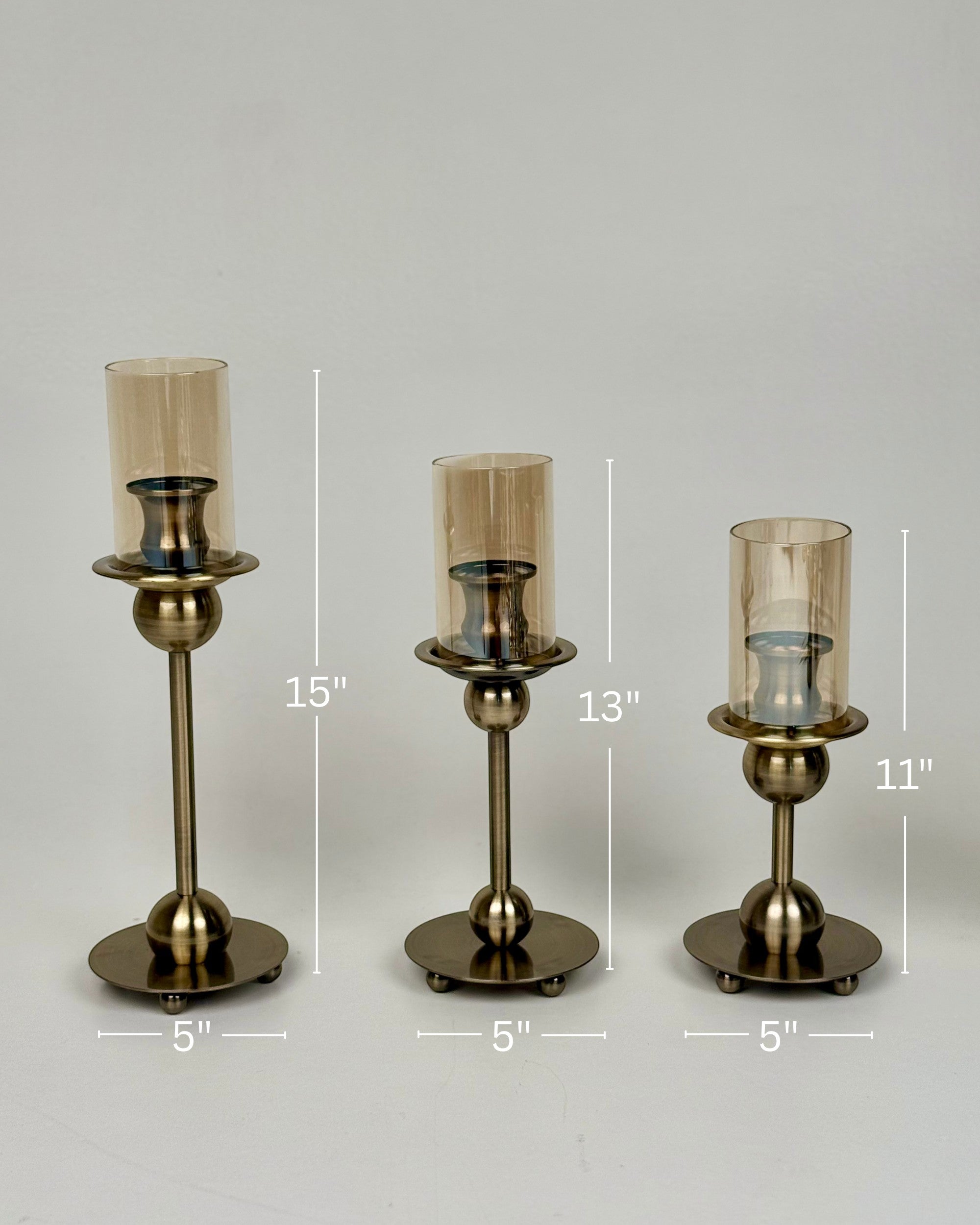 High Objects Seren Column Candle Stand Set, antique brass metal, 3 sizes, amber glass hurricanes, sphere detail, wide base.