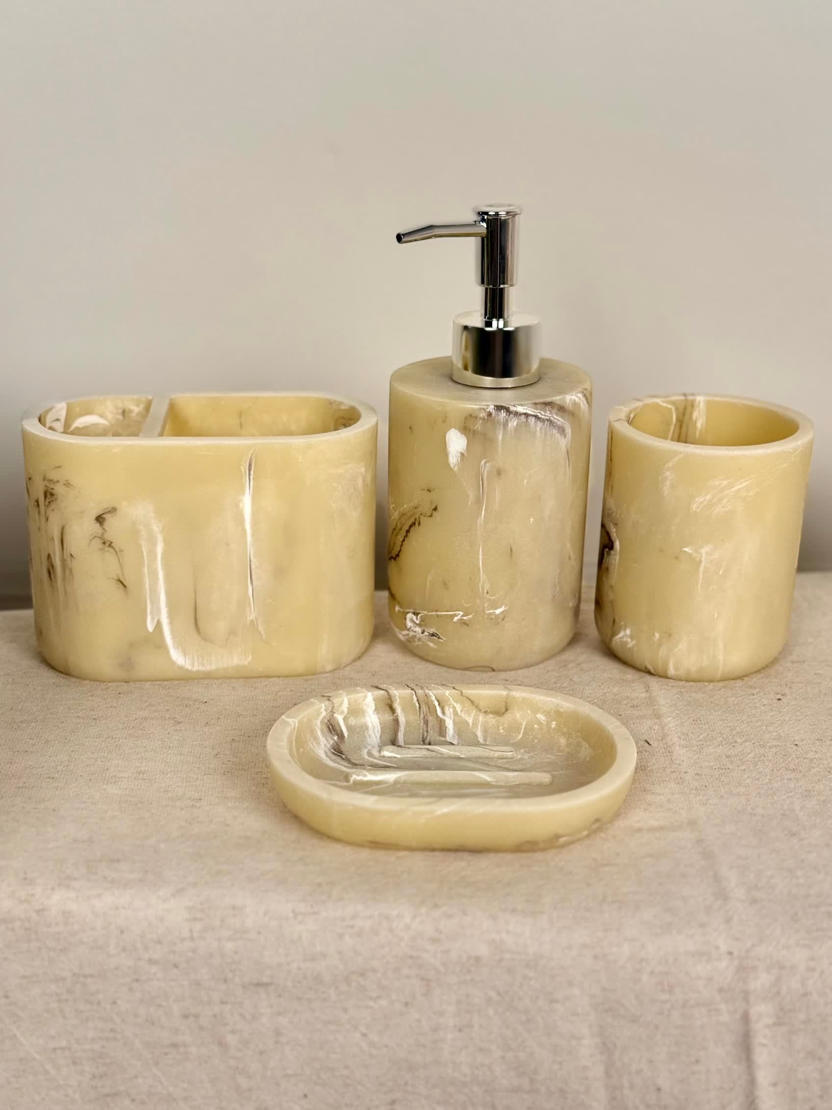 High Objects Veinstone Bathroom Accessory Set in cream with marbled veining. Includes soap dispenser, toothbrush holder, cup, and soap dish.