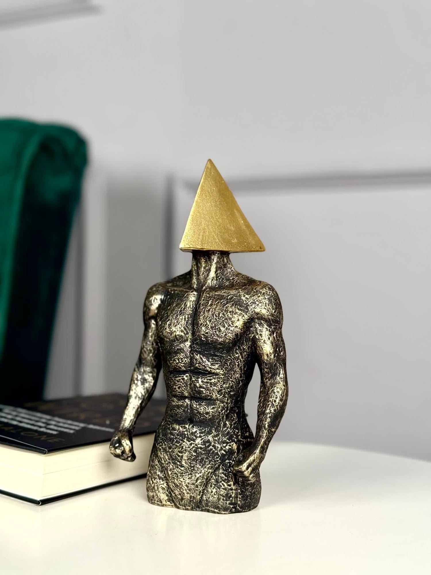 High Objects abstract sculpture of a muscular torso with a gold triangle head, textured stone finish.