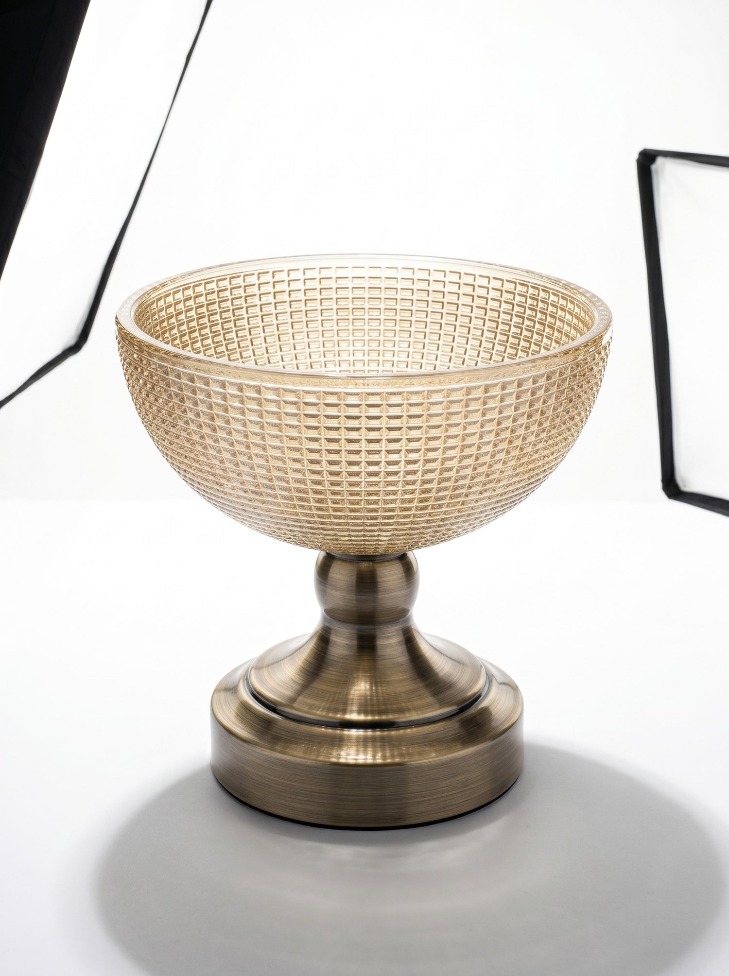 High Objects textured amber glass bowl with a brass pedestal base, perfect for decorative use.