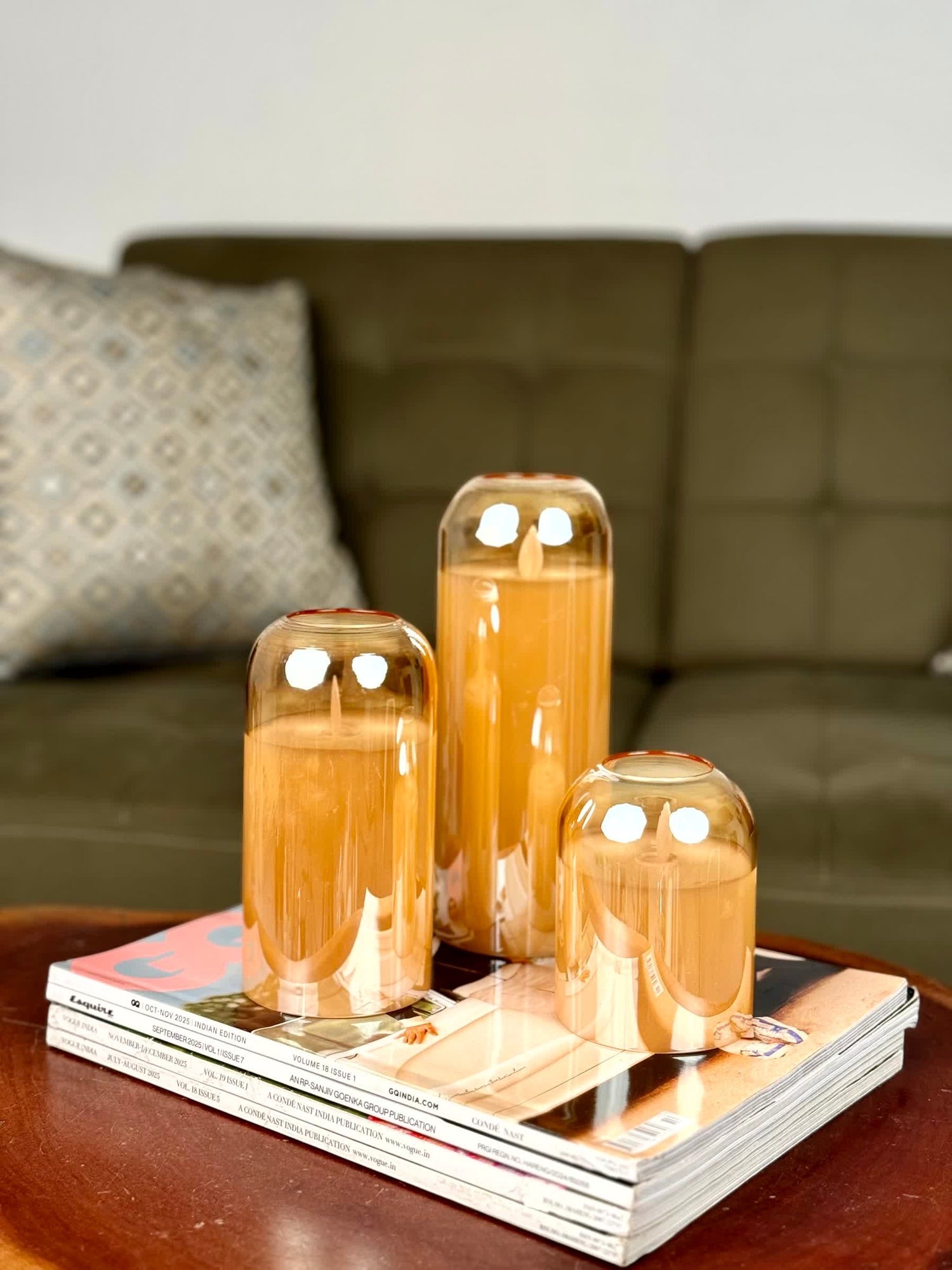 High Objects amber glass LED candles set of 3 on stack of magazines, creating warm ambient lighting.