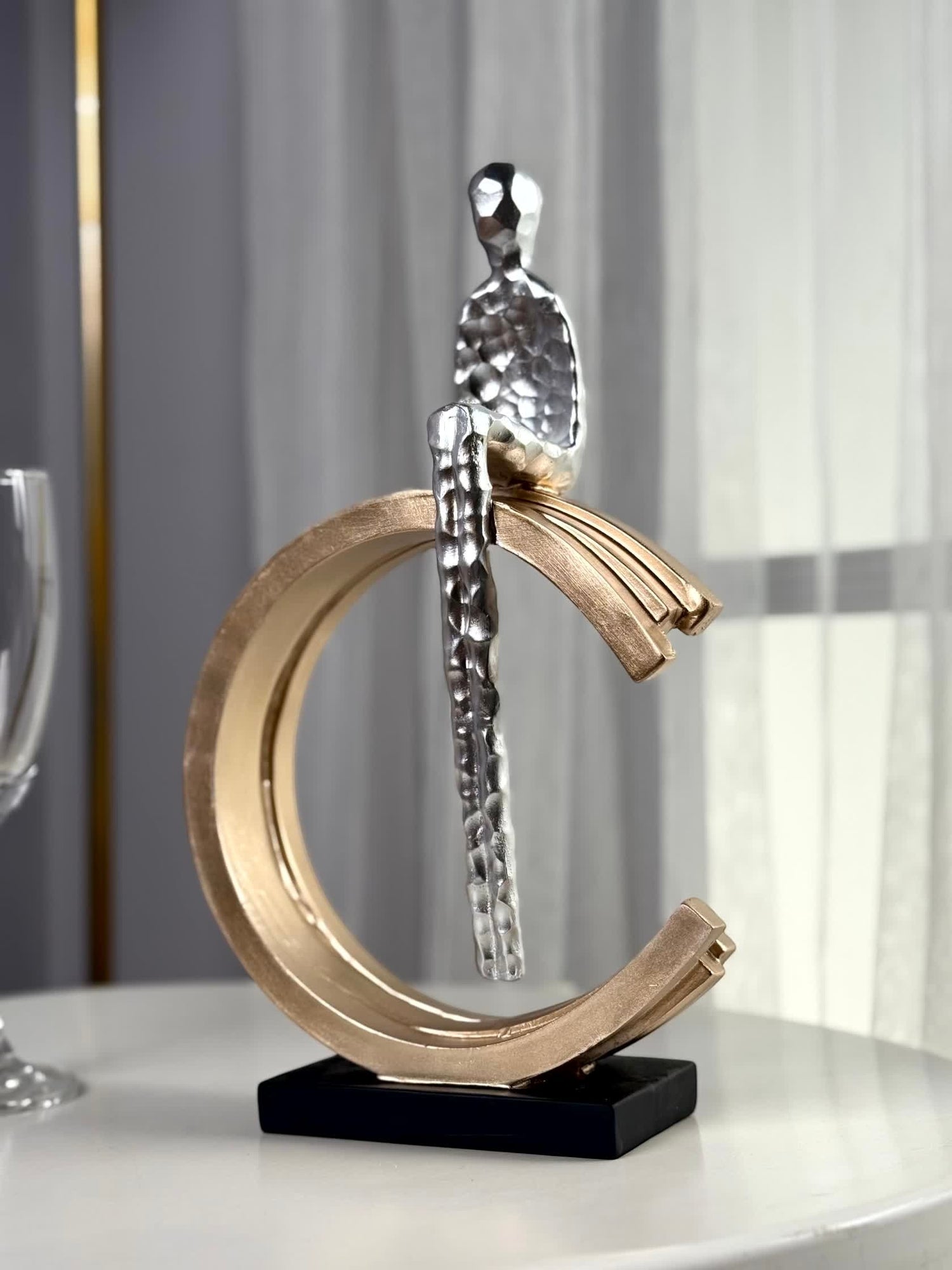 High Objects Arc of Solitude showpiece: minimalist silver figure seated on gold arc, black base. Modern polyresin decor.