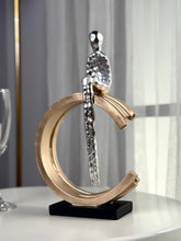 High Objects Arc of Solitude showpiece: minimalist silver figure seated on gold arc, black base. Modern polyresin decor.