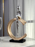 High Objects Arc of Solitude showpiece: minimalist silver figure seated on gold arc, black base. Modern polyresin decor.