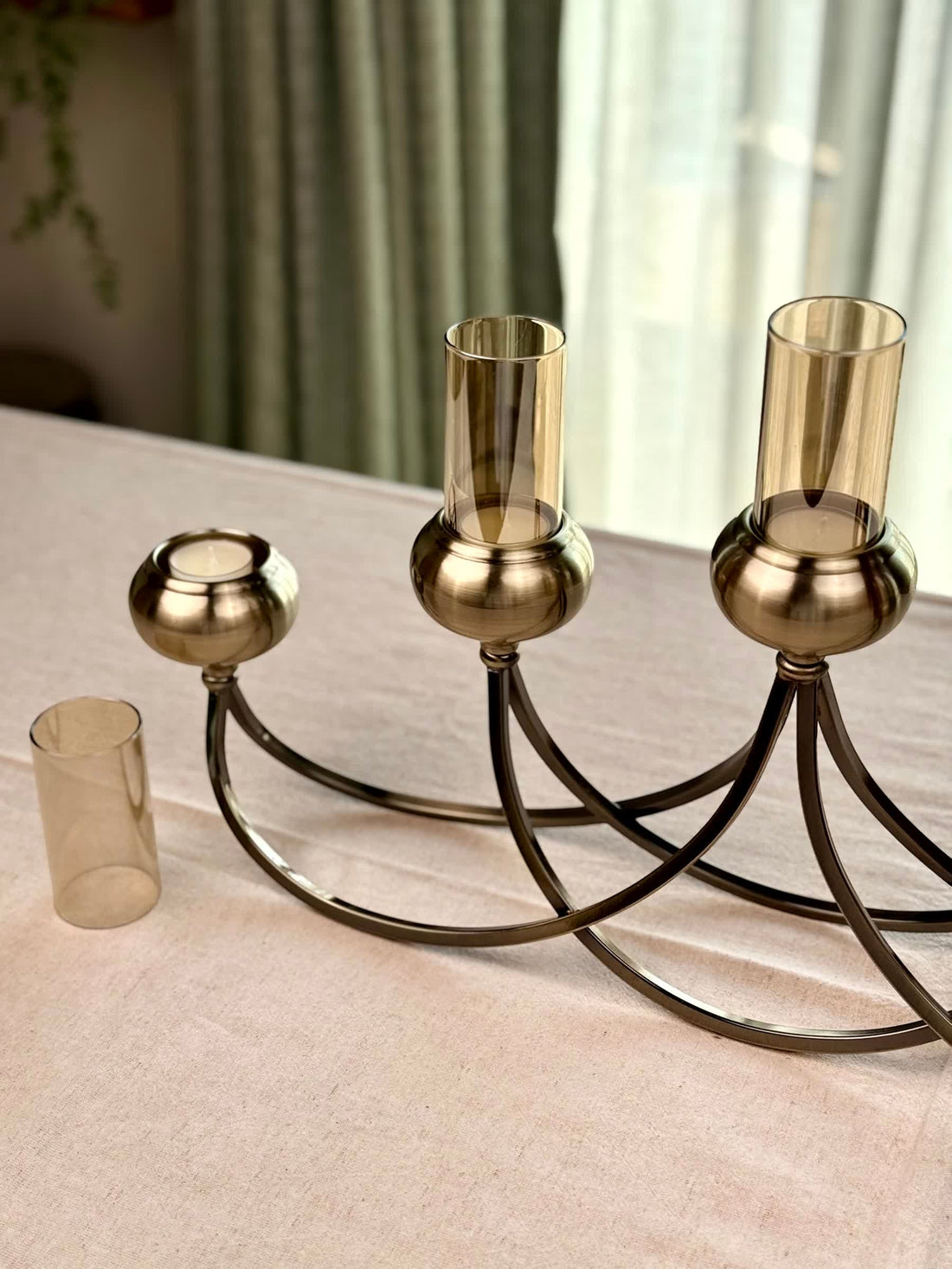 High Objects Aria Five-Arm Candle Stand with amber glass holders and antique brass finish. Sculptural metal design.