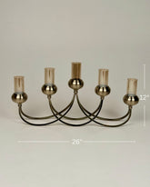 High Objects Aria Five-Arm Candle Stand with tinted glass holders and antique brass finish. 26" W x 12" H.