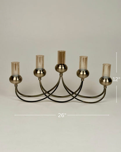 High Objects Aria Five-Arm Candle Stand with tinted glass holders and antique brass finish. 26" W x 12" H.