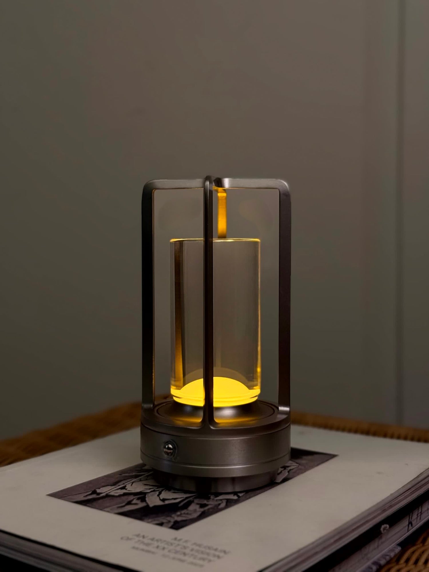 High Objects Aria Frame Table Lamp with clear glass shade and brushed metal base, emits warm yellow light.