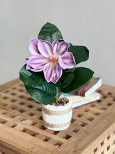 High Objects artificial lily plant with purple and white petals, green leaves, in a white striped ceramic pot with pebbles.