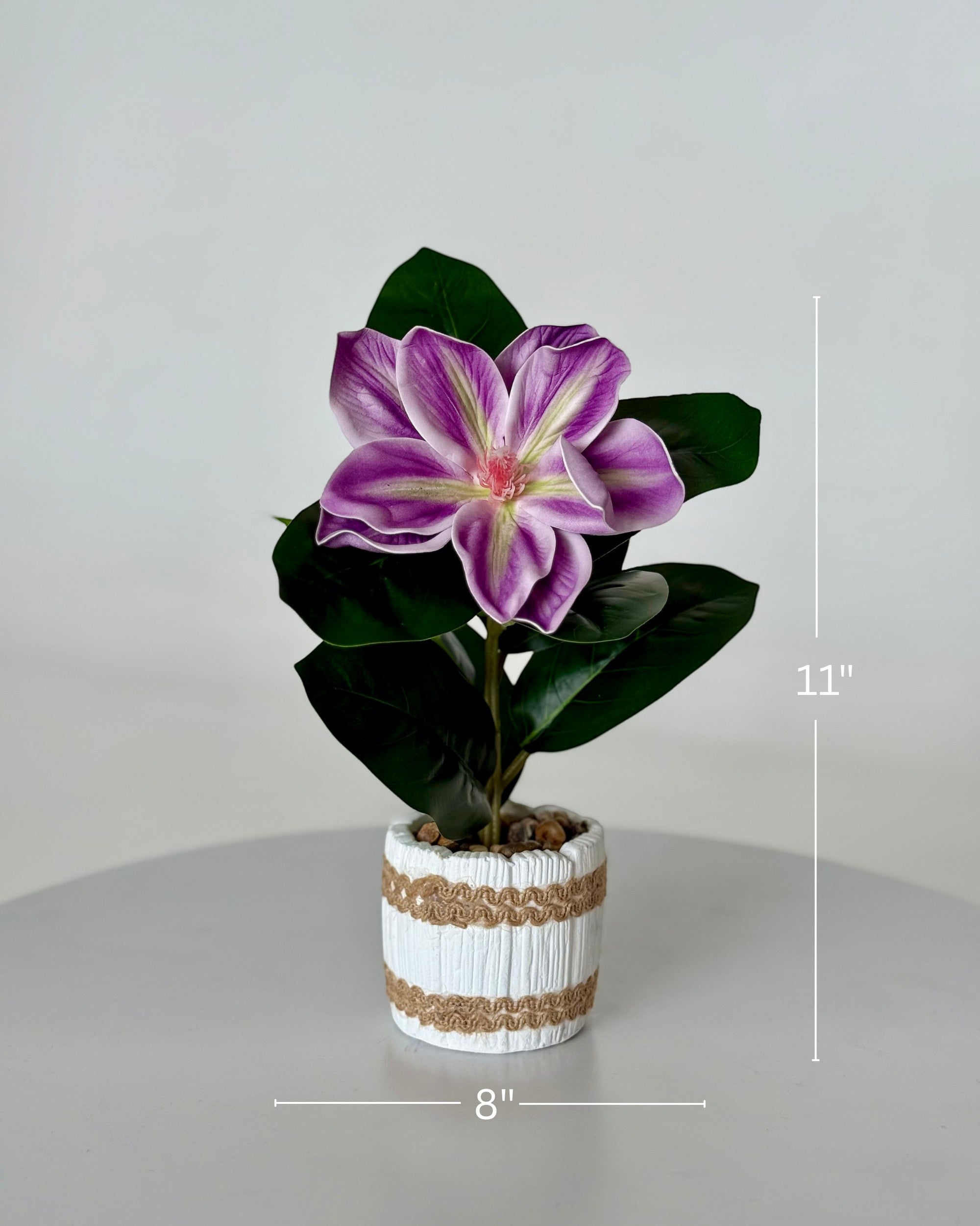 High Objects artificial purple and white lily plant in a white striped ceramic pot with pebbles. 11" H x 8" W.