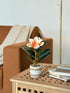 High Objects artificial lily plant with white and orange bloom in a striped ceramic pot with pebbles.