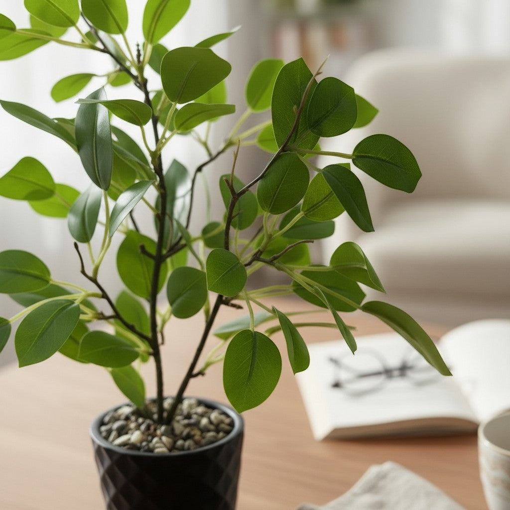 High Objects artificial plant with vibrant green leaves in a textured black pot, styled on a wooden table with a book and mug.