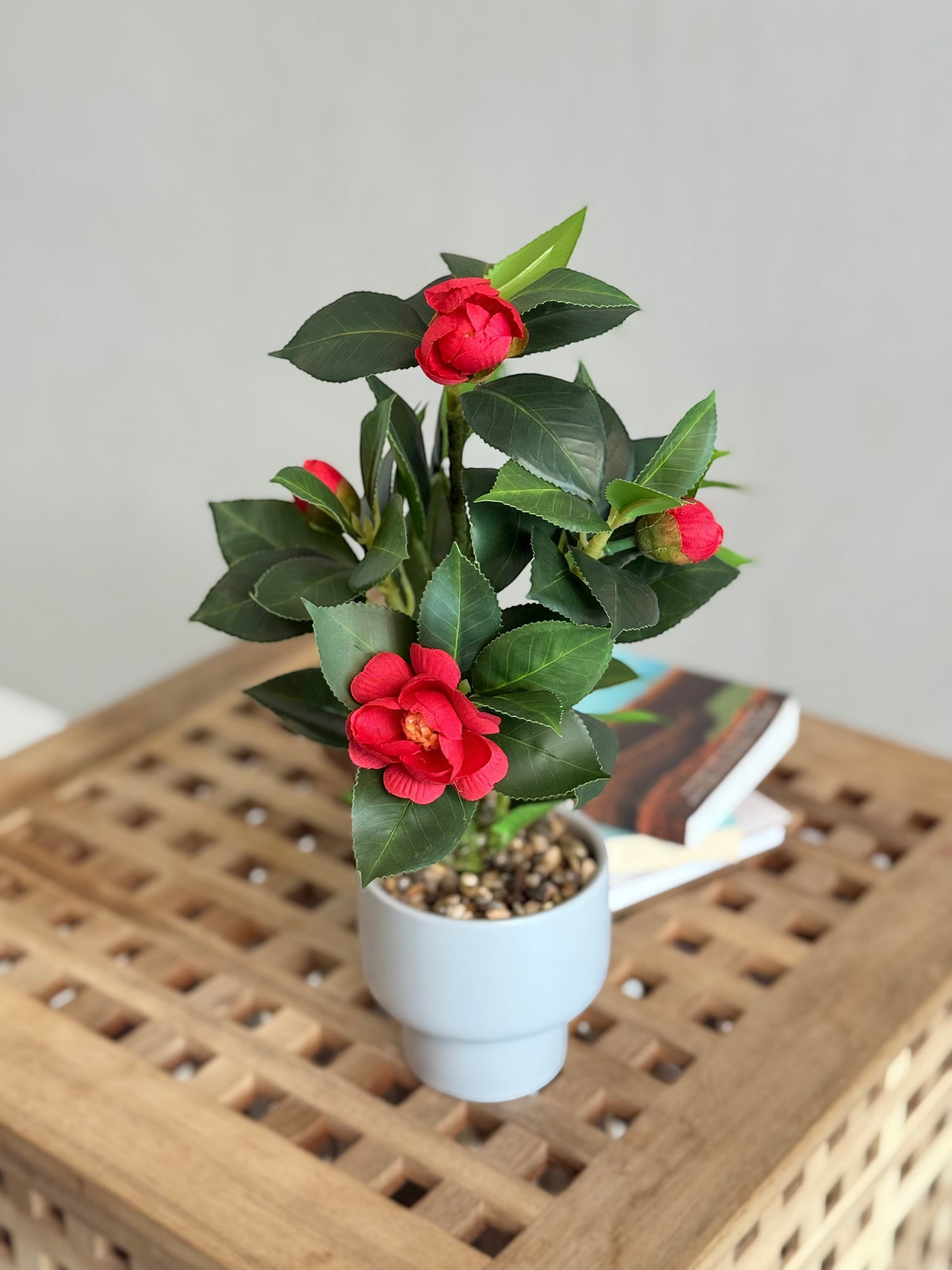 High Objects Artificial Scarlet Camellia Plant with vibrant red blooms and lush green leaves in a white pot.