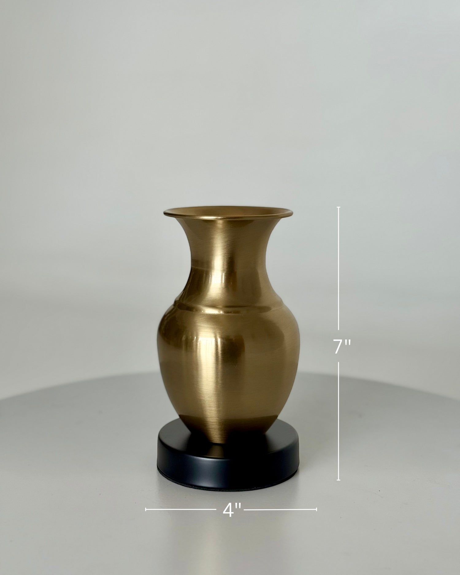High Objects Aurelia Vase, brushed gold metallic finish, rounded body, flared neck, on a black base. 7" H x 4" W.