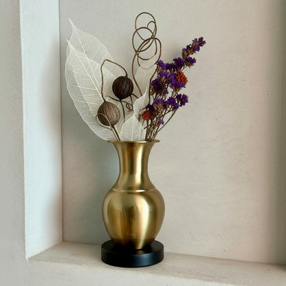 High Objects Aurelia Vase: brushed gold metallic vase with flared neck on black base, holding dried bunny tail grass.
