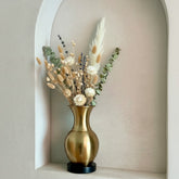 High Objects Aurelia Vase: Brushed gold metallic vase with rounded body, flared neck, and black base, holding dried floral arrangement.