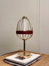 High Objects Aurette Cage Table Lamp with gold wire cage, leather band, and gold base. Modern sculptural design.