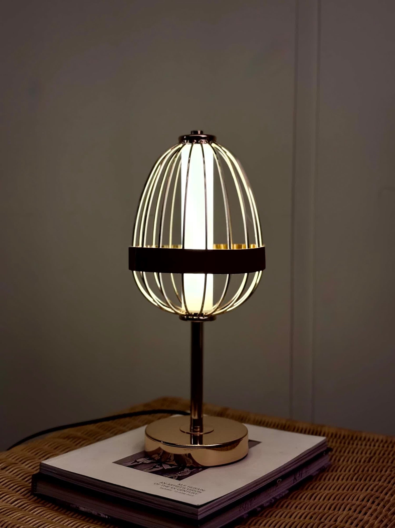 High Objects Aurette Cage Table Lamp with gold wire cage, leather band, and gold base. Modern sculptural design.