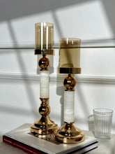 High Objects Aurora Column Candle Stand Set with amber glass shades and gold accents on white marble-inspired columns.