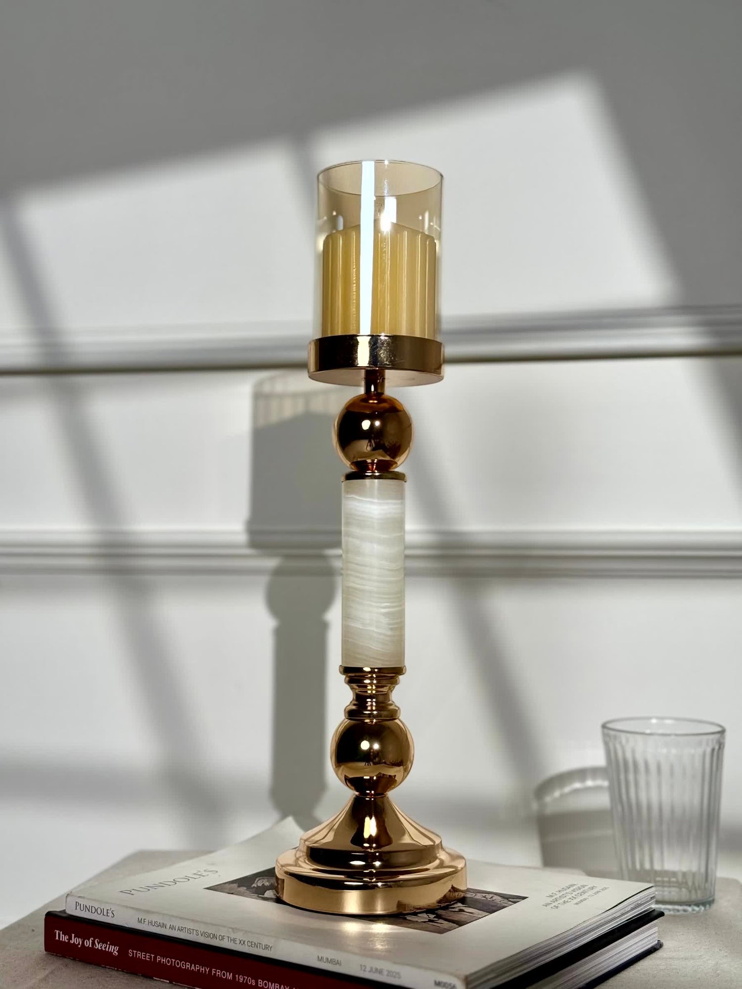 High Objects Aurora Column Candle Stand Set with amber glass holder and white stone-inspired column, polished gold accents.