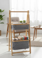 High Objects natural bamboo frame storage organizer with two grey fabric baskets holding towels, books, and plants.