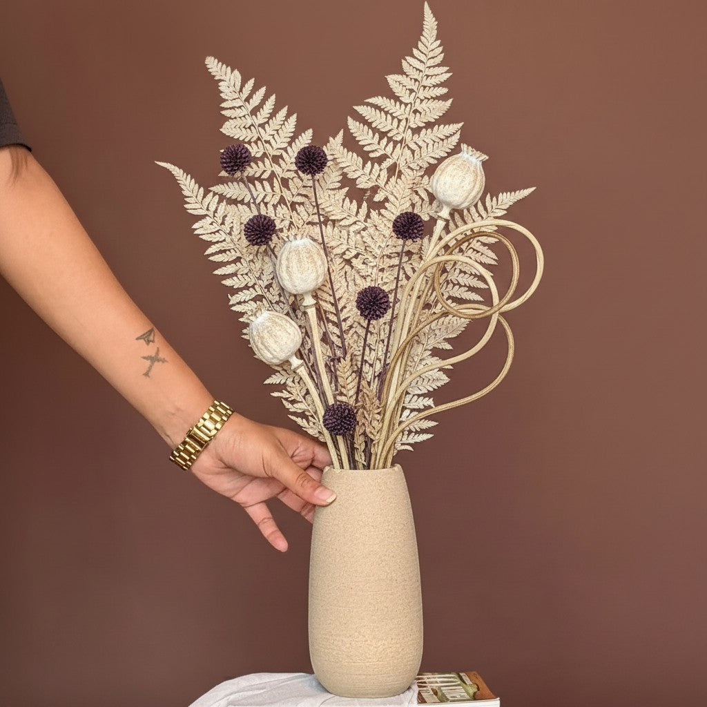 High Objects beige ceramic vase with wavy rim, holding dried eucalyptus and pampas grass. Hand with gold watch.