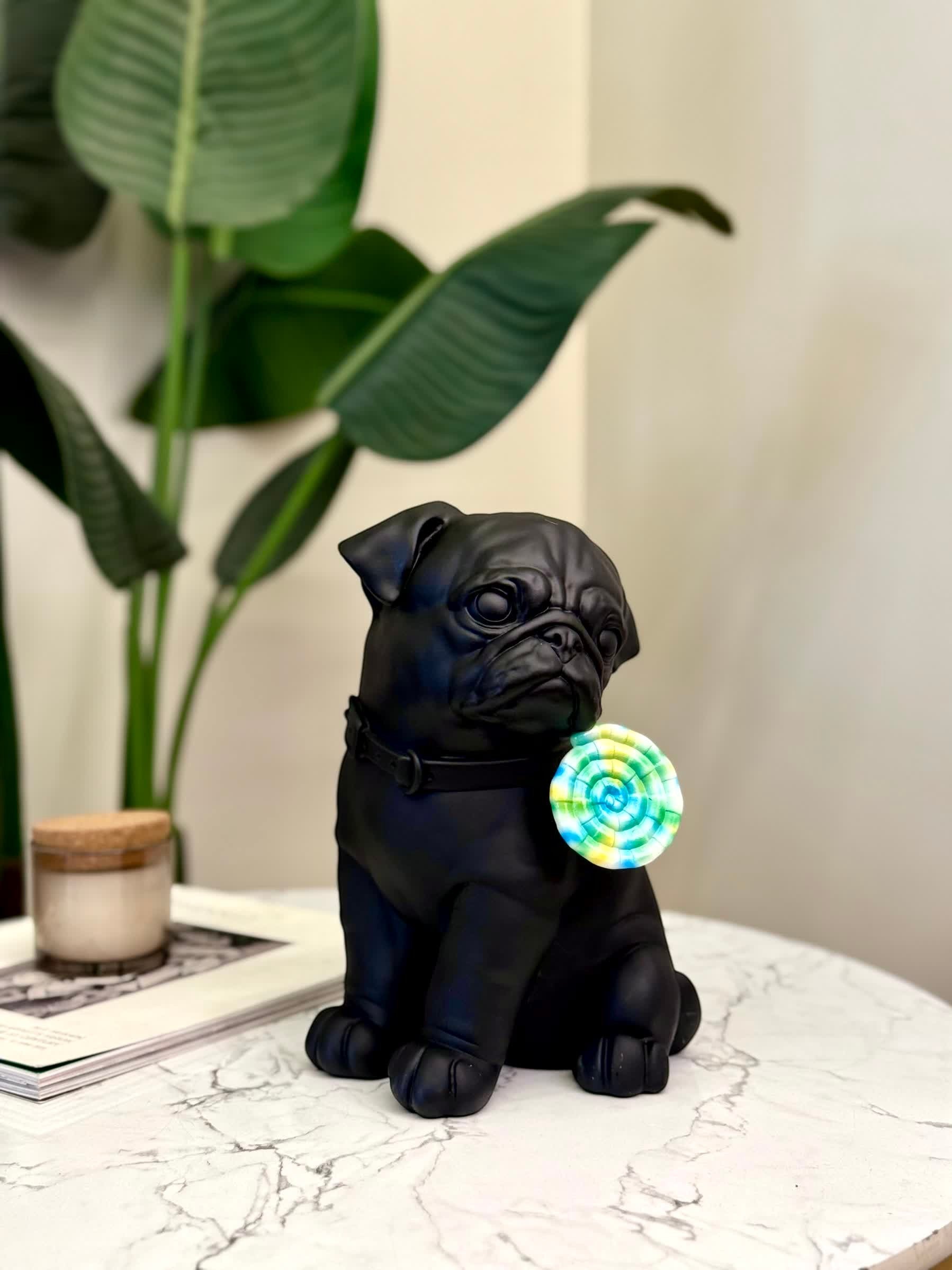 High Objects matte black pug showpiece holding a colorful swirl lollipop, modern decor accent
