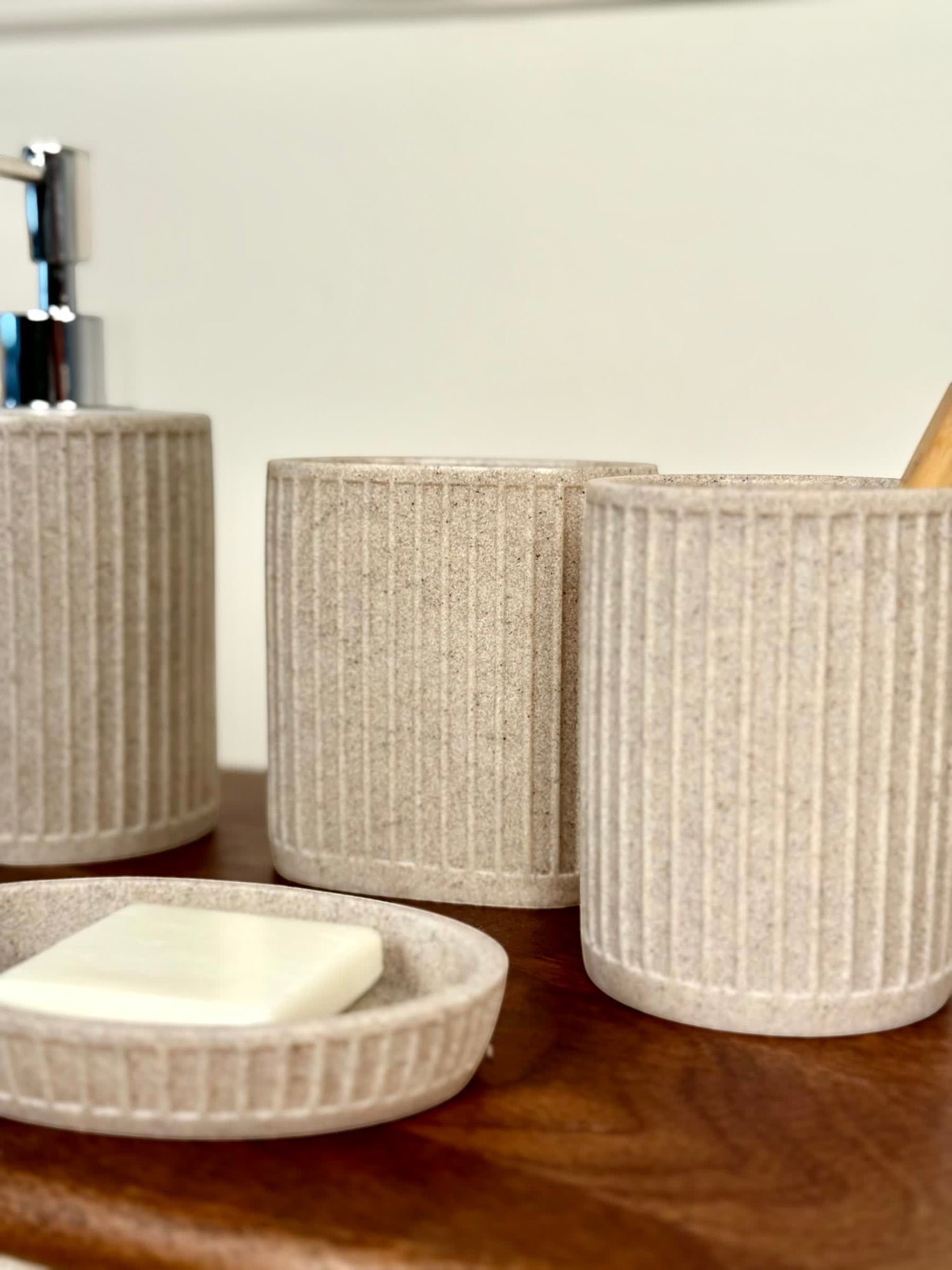 High Objects Calmridge Bathroom Accessory Set in speckled beige stone with ribbed texture. Includes soap dish, dispenser, and cups.
