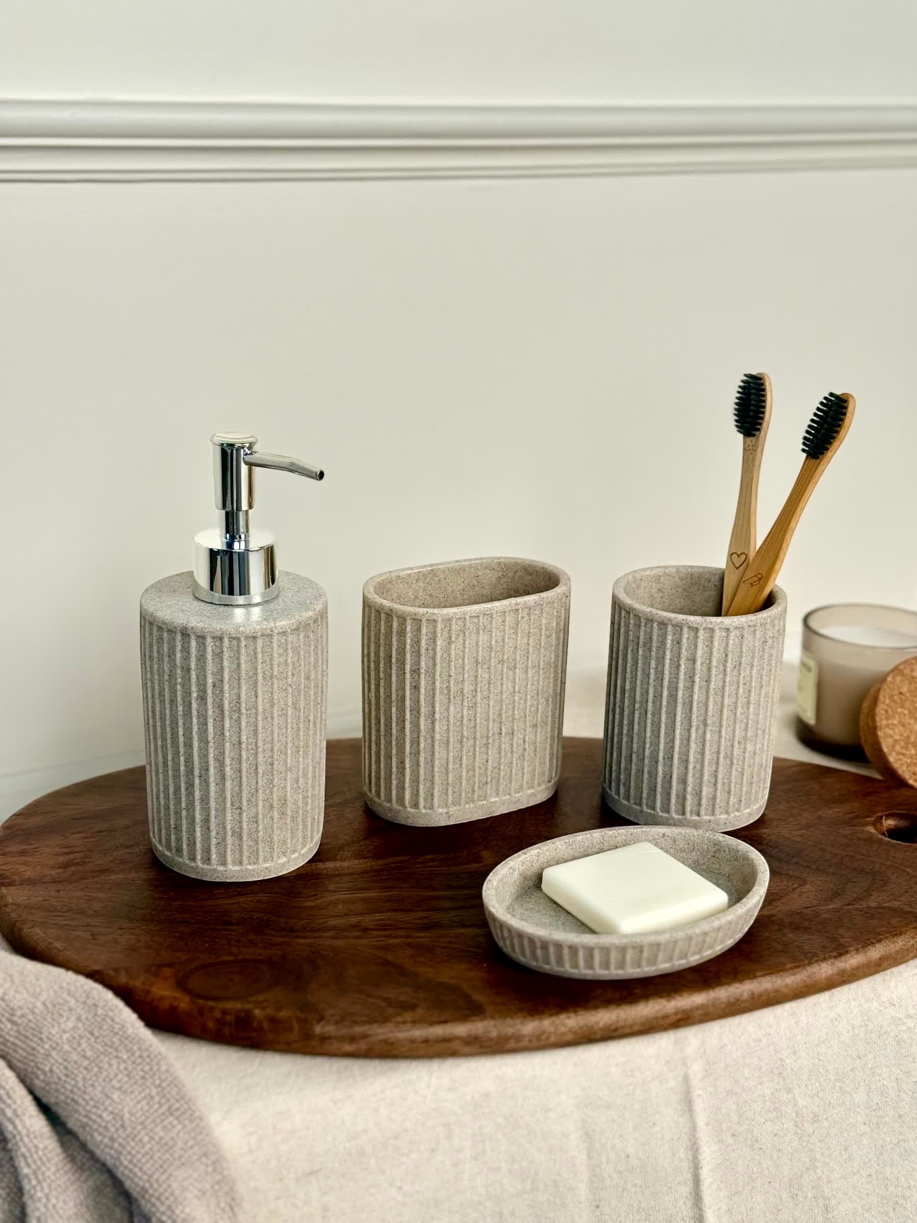 High Objects Calmridge bathroom accessory set in speckled grey stone, featuring a soap dispenser, soap dish, and toothbrush holder with bamboo toothbrushes.
