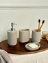 High Objects Calmridge bathroom accessory set in speckled grey stone, featuring a soap dispenser, soap dish, and toothbrush holder with bamboo toothbrushes.