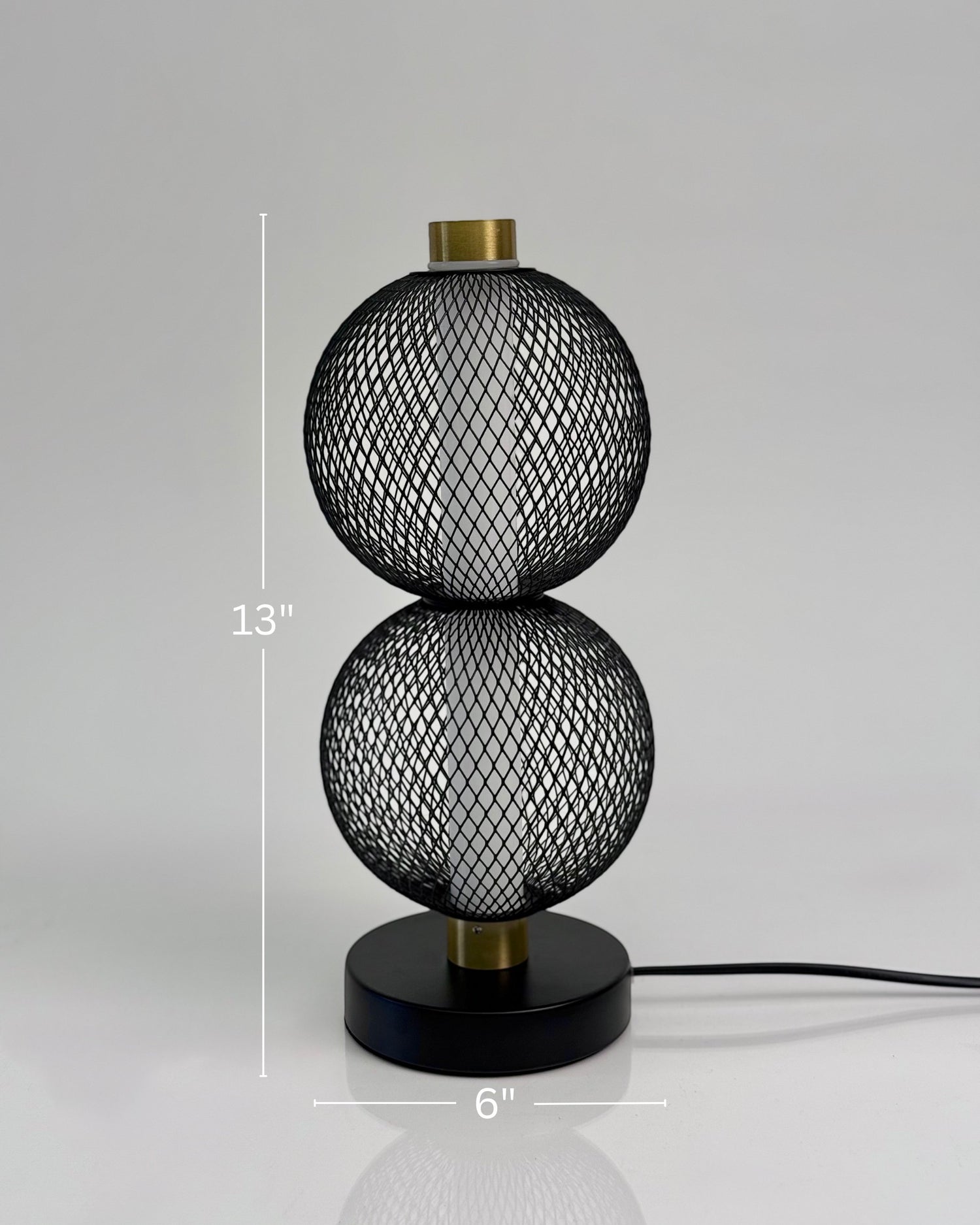 High Objects Celeste Duo Mesh Table Lamp with stacked spherical black mesh shades and brushed gold accents on a black base.