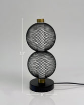 High Objects Celeste Duo Mesh Table Lamp with stacked spherical black mesh shades and brushed gold accents on a black base.