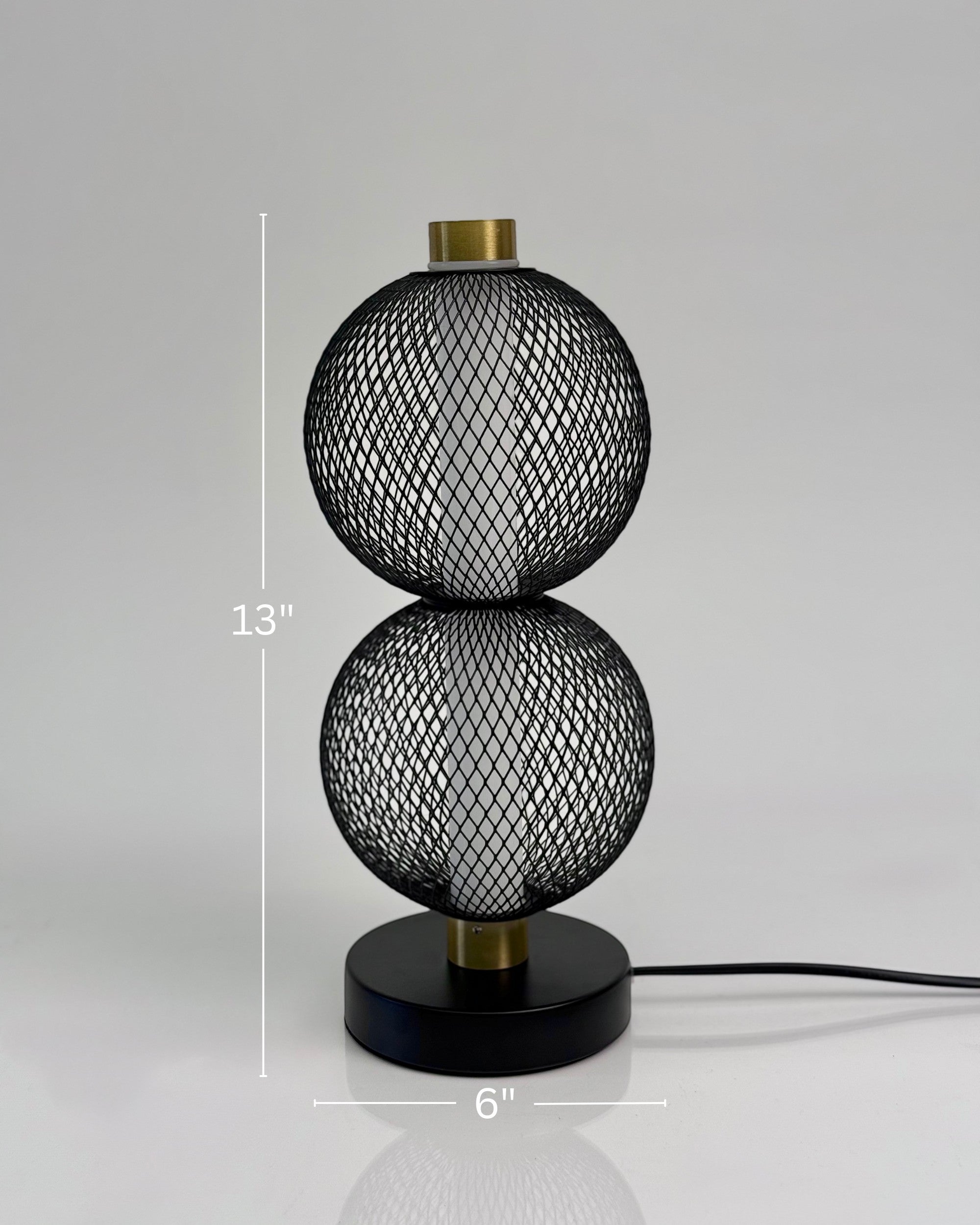 High Objects Celeste Duo Mesh Table Lamp with stacked spherical black mesh shades and brushed gold accents on a black base.